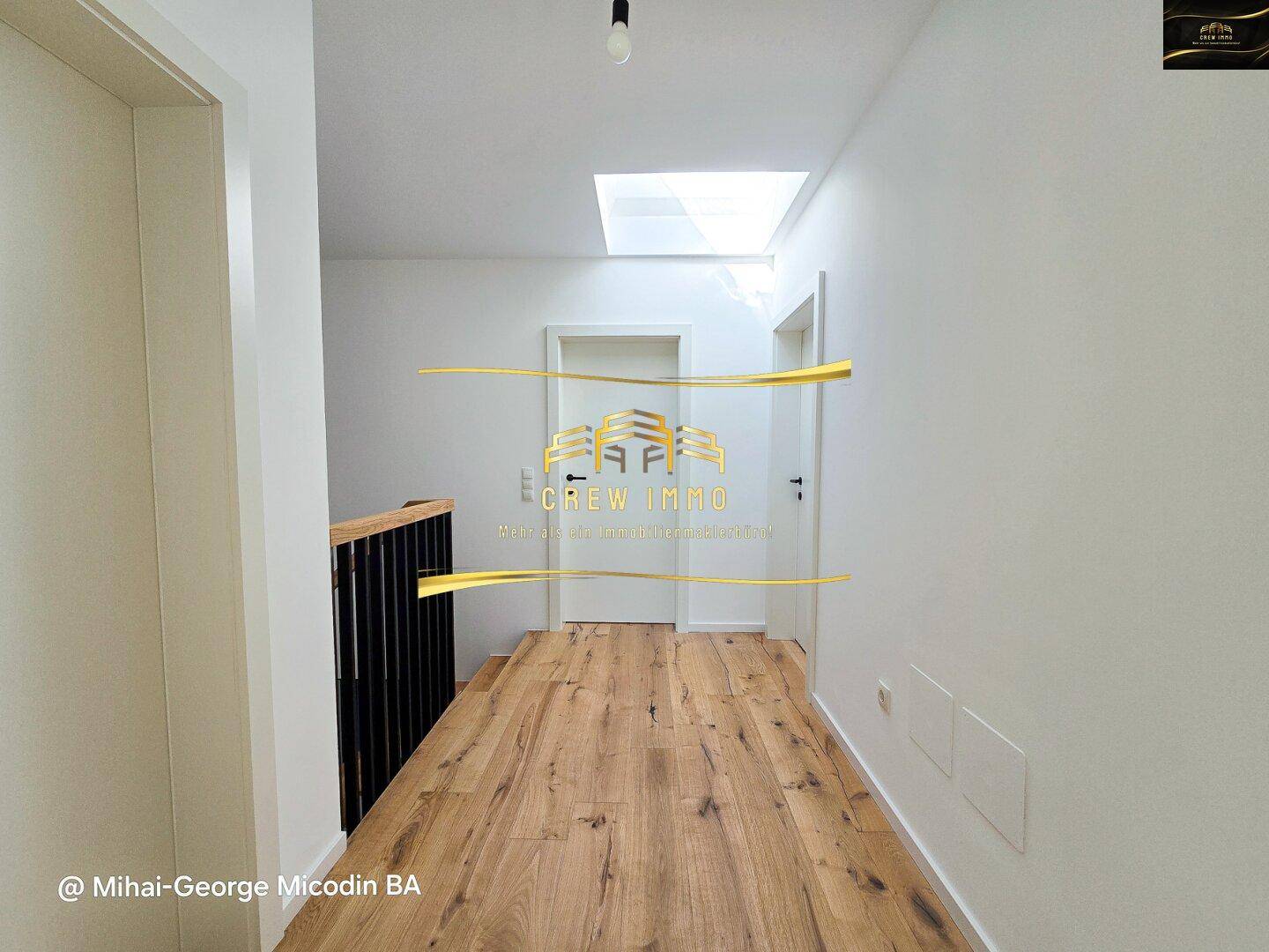 Heller Flur im Obergeschoss mit Holzparkett und einem Oberlicht, das Tageslicht spendet.