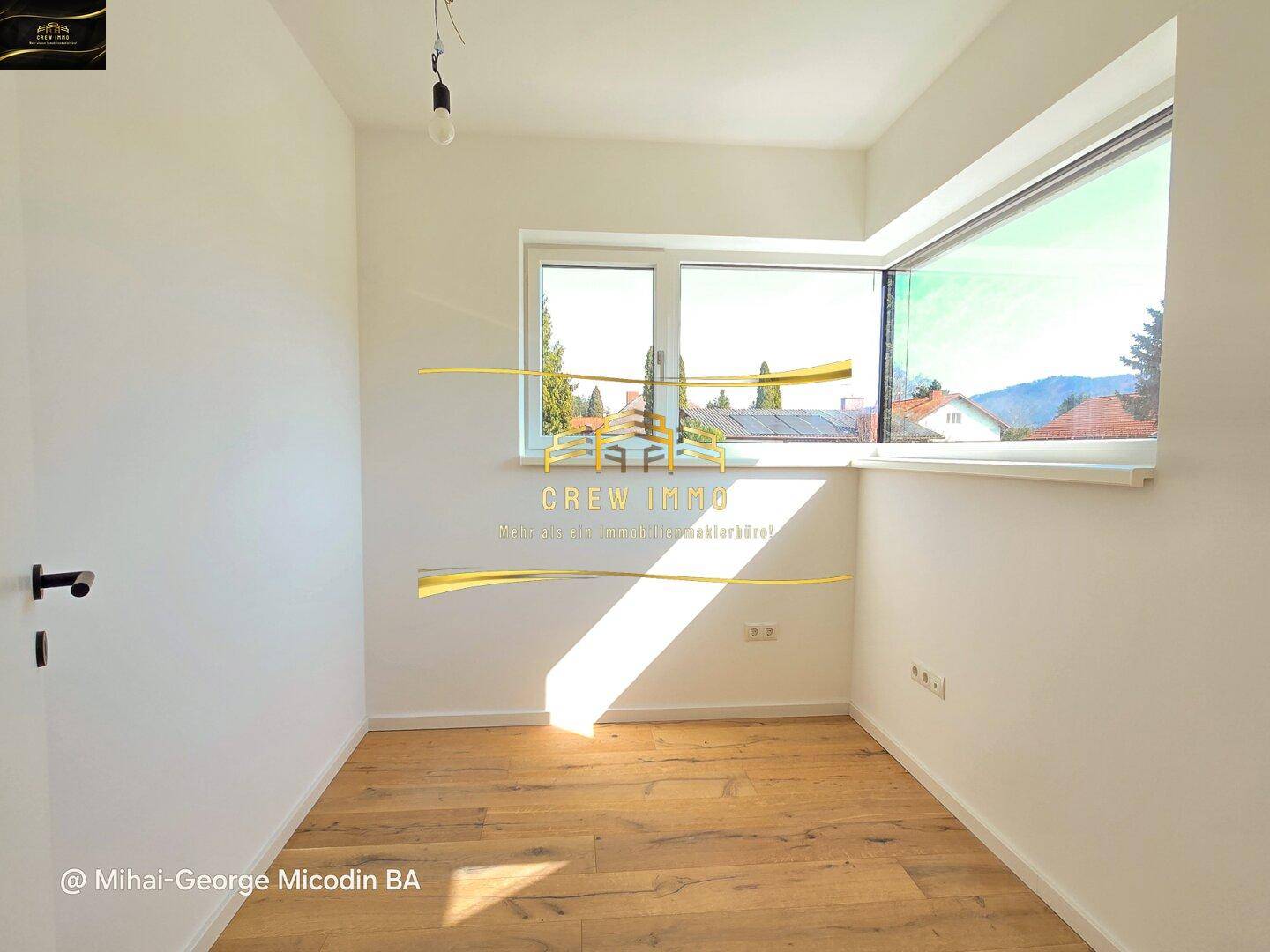 Helles Zimmer mit großen Fenstern und Holzboden, ideal als Schlaf- oder Arbeitszimmer.