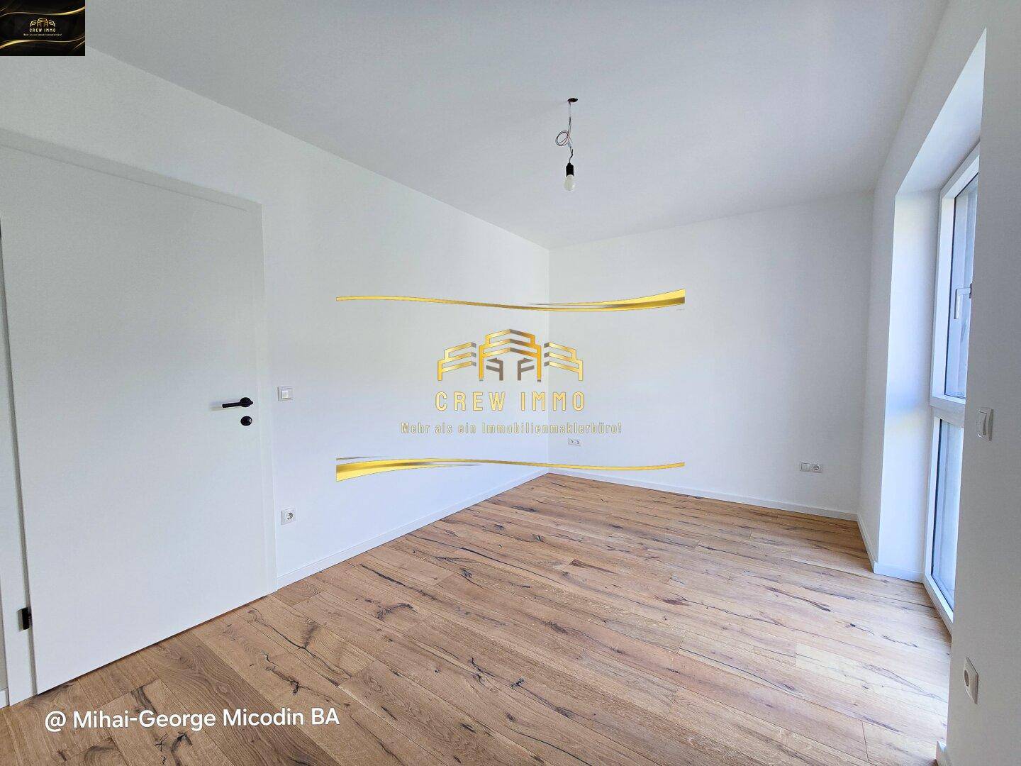 Helles Schlafzimmer mit Holzboden und großen Fenstern, die viel Tageslicht hereinlassen.