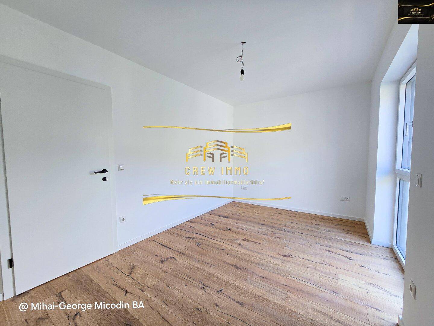 Unmöbliertes Schlafzimmer mit hellem Holzparkett und einem Fenster, das viel Licht hereinlässt.
