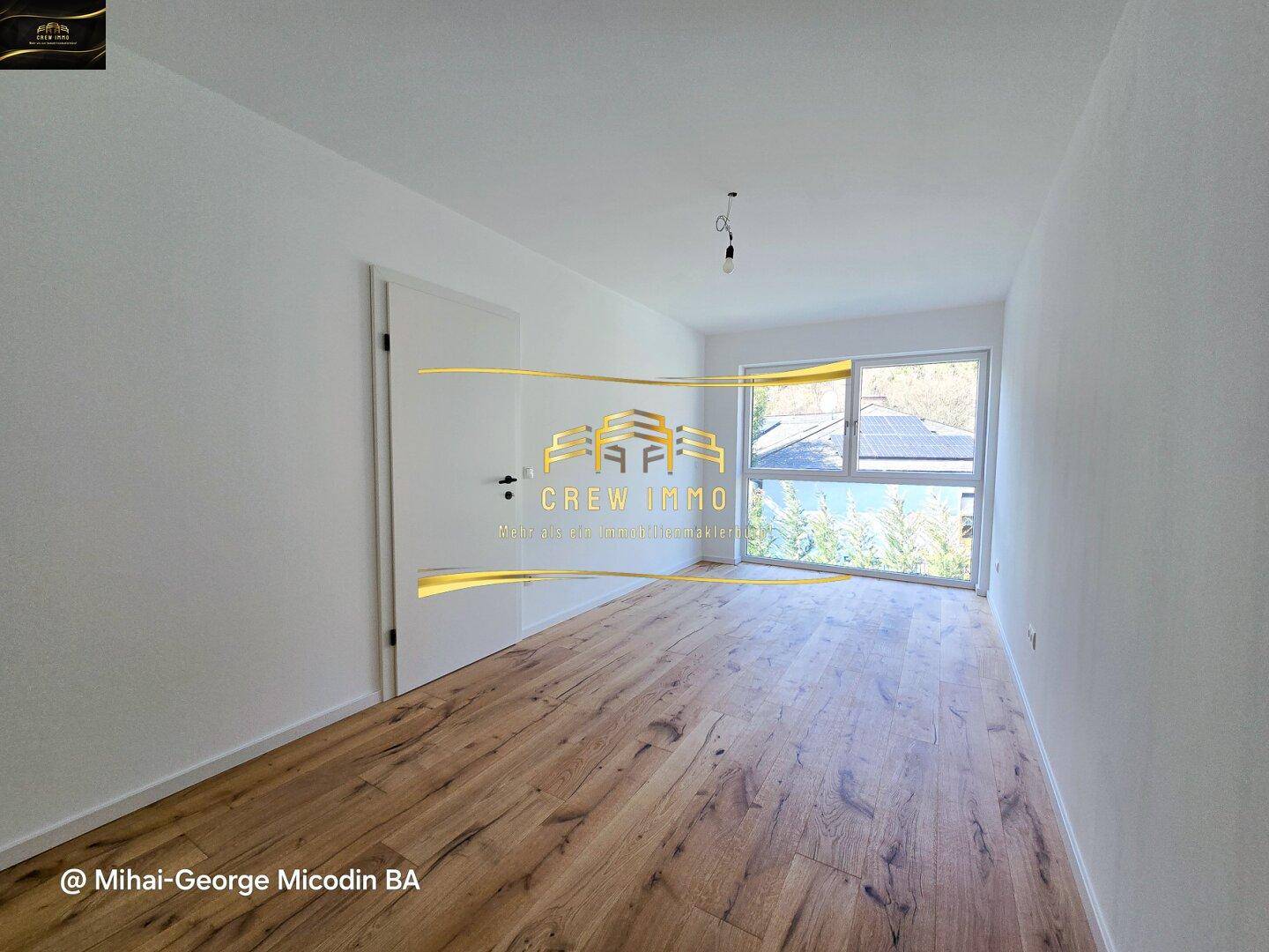 Geräumiges Zimmer mit Holzboden und bodentiefen Fenstern, bietet einen schönen Ausblick.