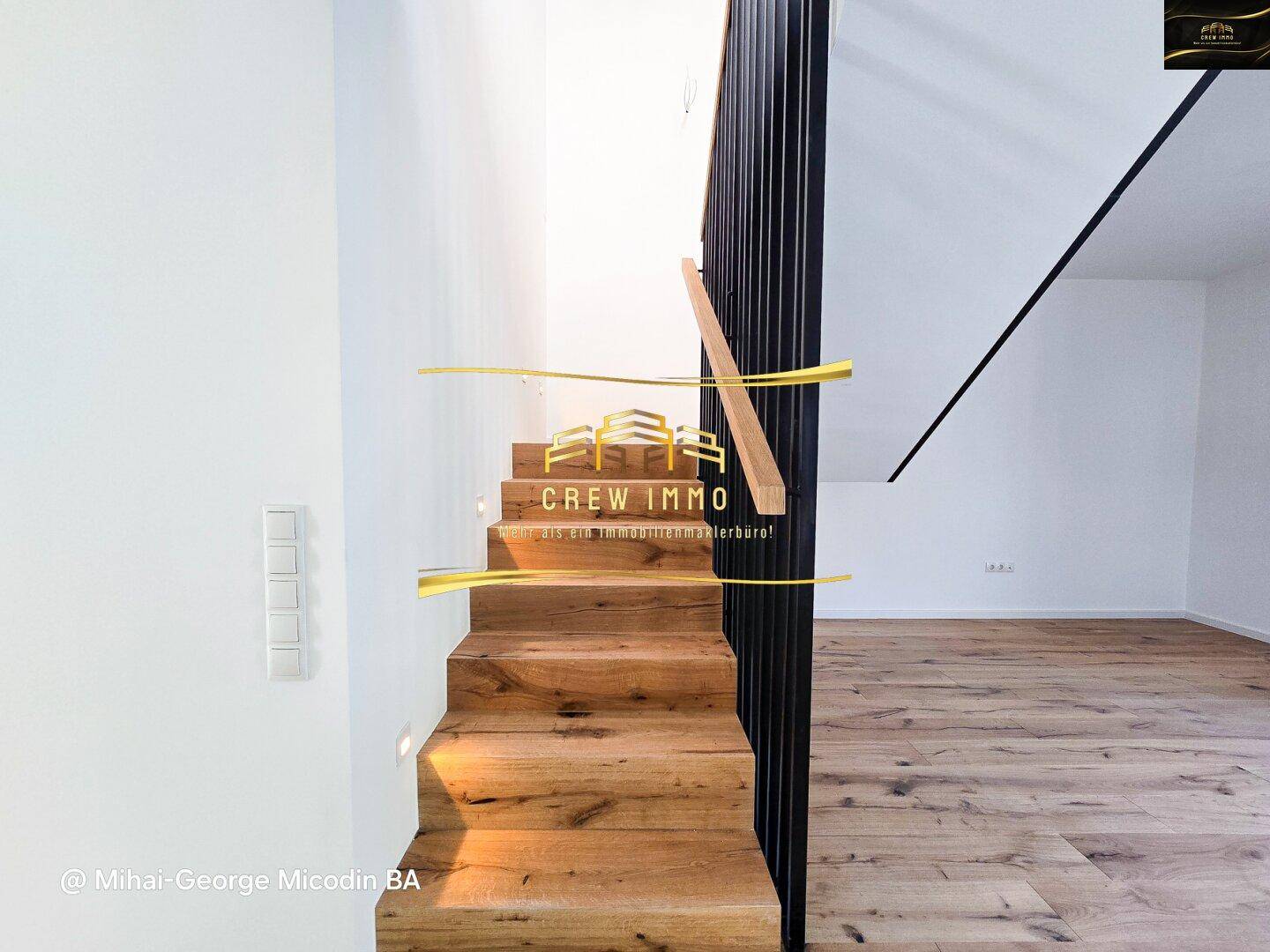 Detailansicht der modernen Holztreppe mit elegantem schwarzem Geländer und integrierter Beleuchtung.