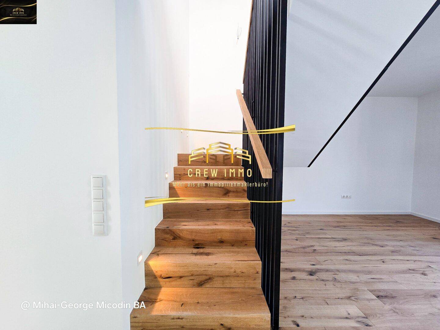 Moderne Holztreppe mit schwarzem Geländer, die die verschiedenen Ebenen des Hauses verbindet.