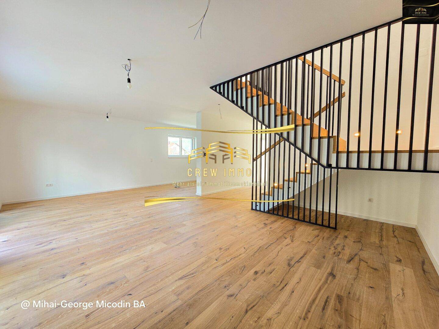 Moderne Holztreppe mit schwarzem Geländer in einem hellen Wohnbereich mit Parkettboden.