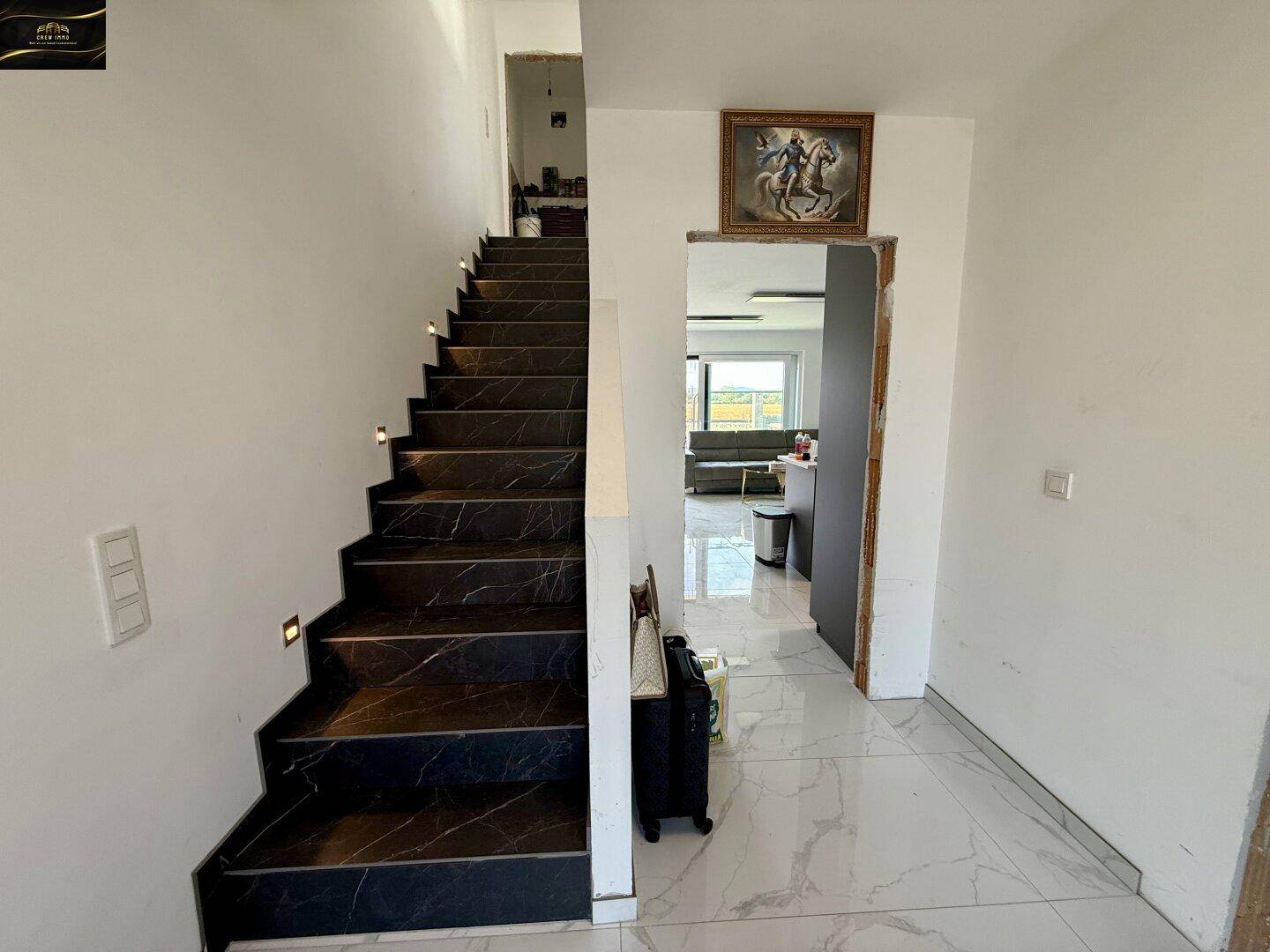 Eingangsbereich mit eleganter Treppe und Blick in den offenen Wohnbereich.