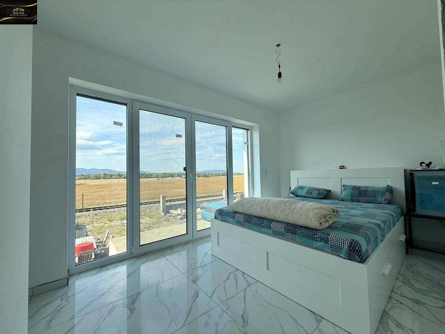 Schlafzimmer mit großem Bett, Fliesenboden und weitem Blick auf die Landschaft.