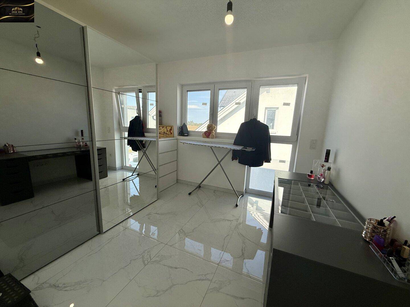 Geräumiges Zimmer mit Spiegelschränken, Fliesenboden und großen Fenstern.