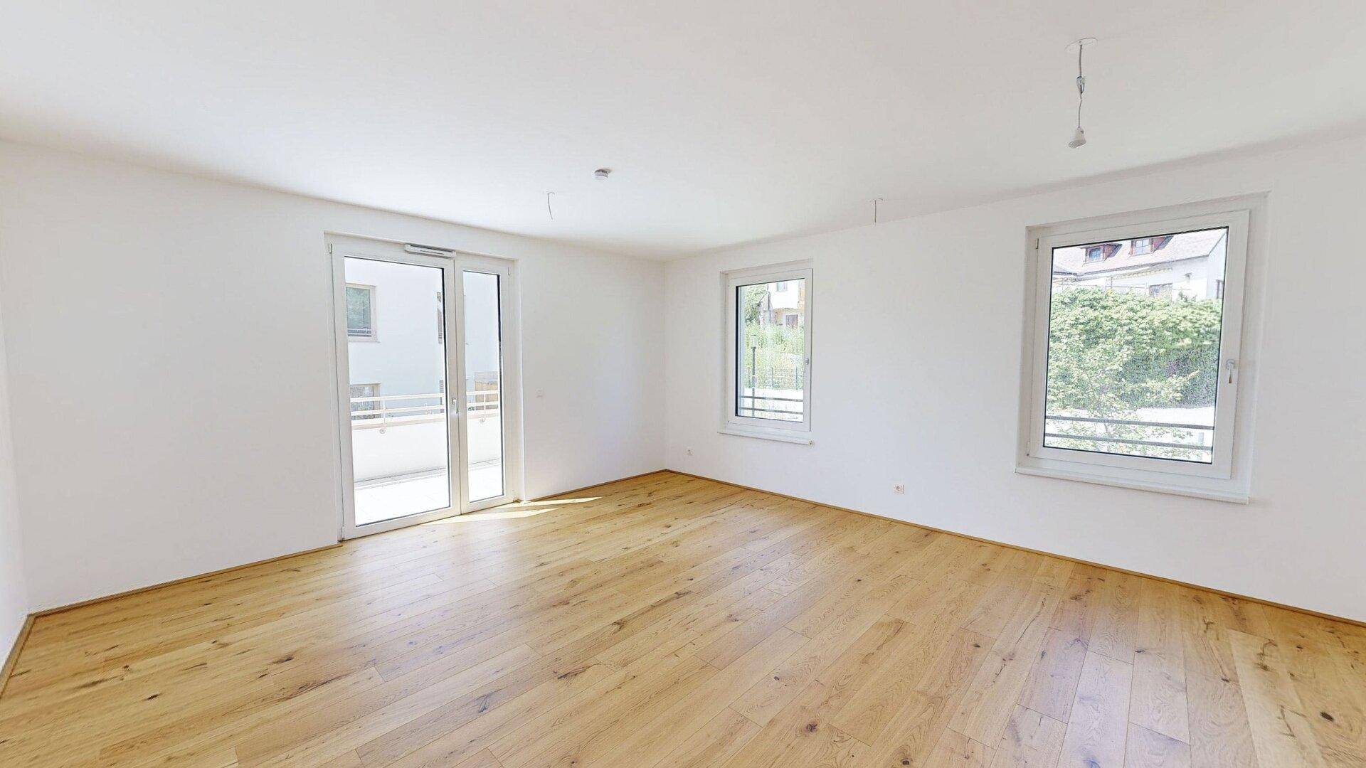 Heller Wohnraum mit Holzboden und Zugang zu einem Balkon, ideal für entspannte Stunden.