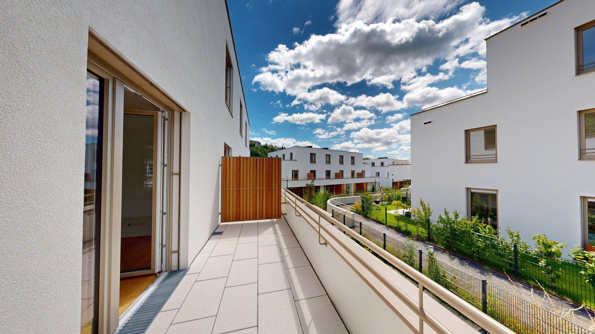 Große, sonnige Terrasse mit Blick auf die moderne Wohnanlage und grüne Umgebung.