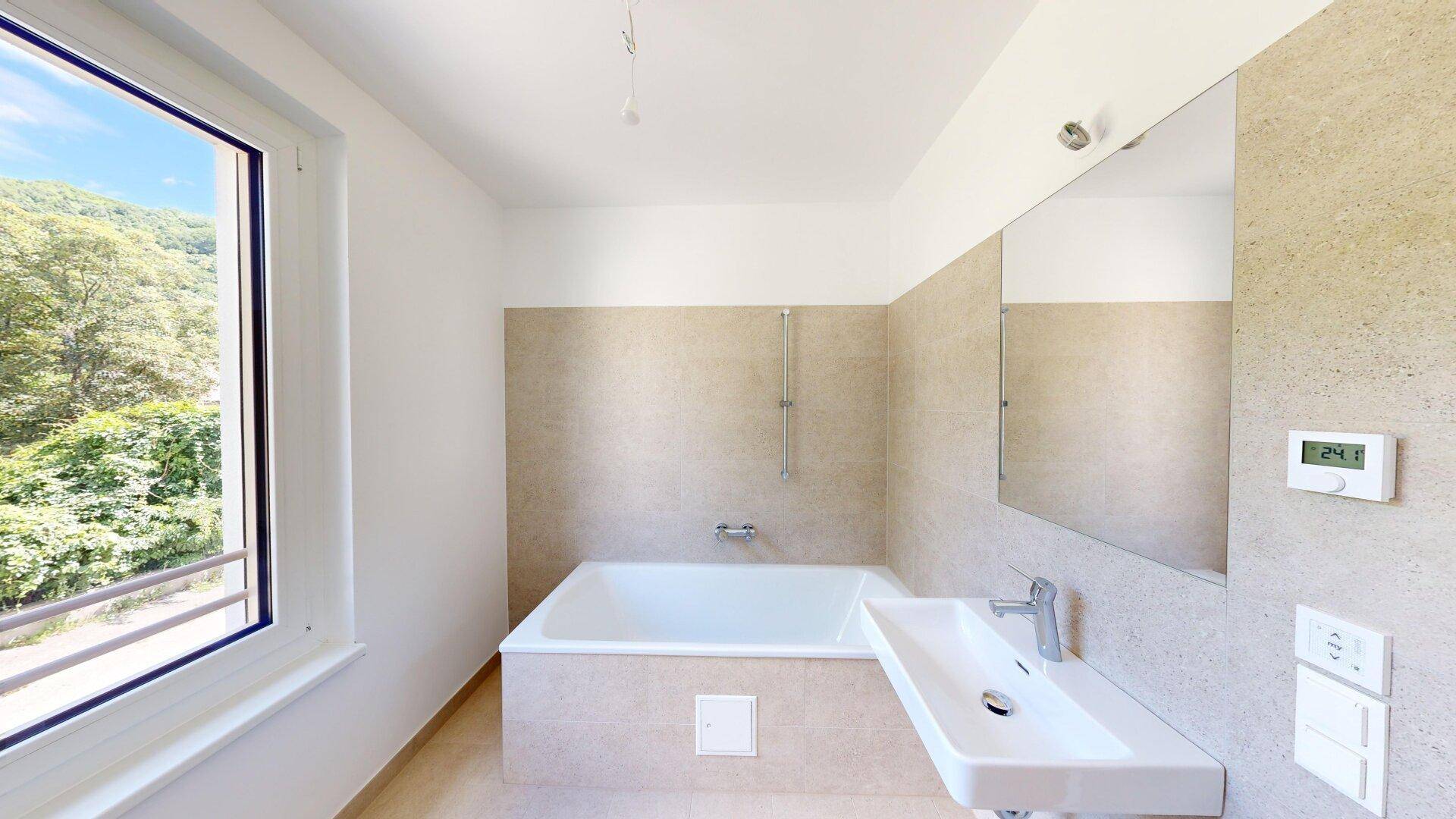 Modernes Badezimmer mit Badewanne, Einzelwaschbecken und großem Fenster mit Bergblick.