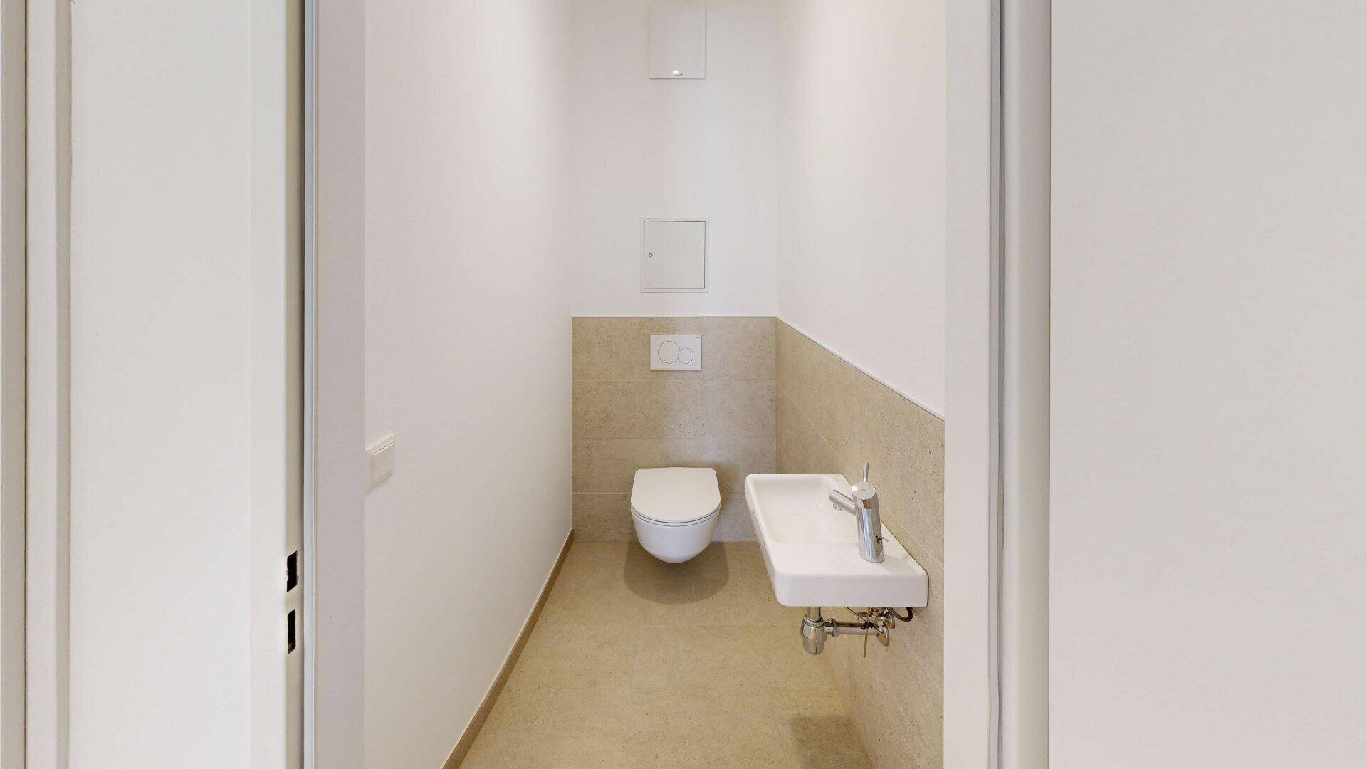Funktionelles Gäste-WC mit wandhängender Toilette und kleinem Waschbecken in neutralen Farben.
