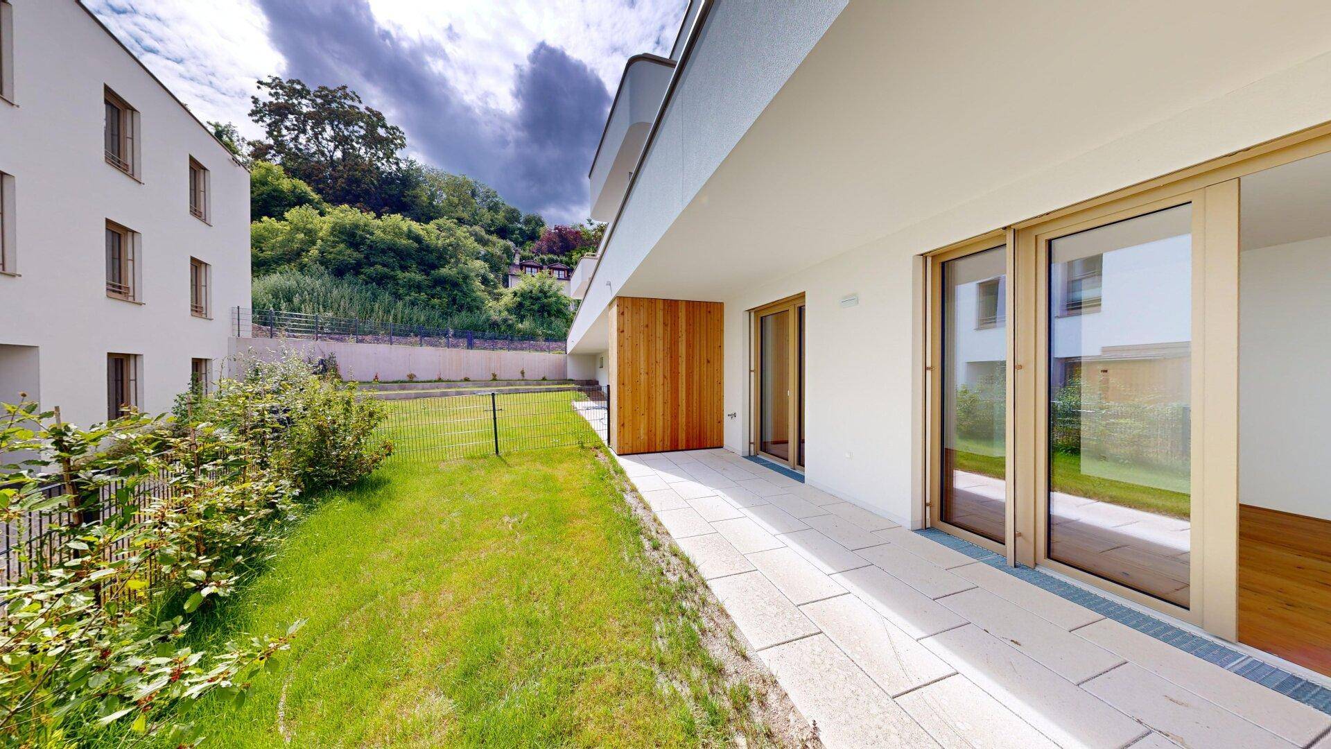 Terrasse mit angrenzendem Gartenbereich und Blick auf die umliegende Hügellandschaft.