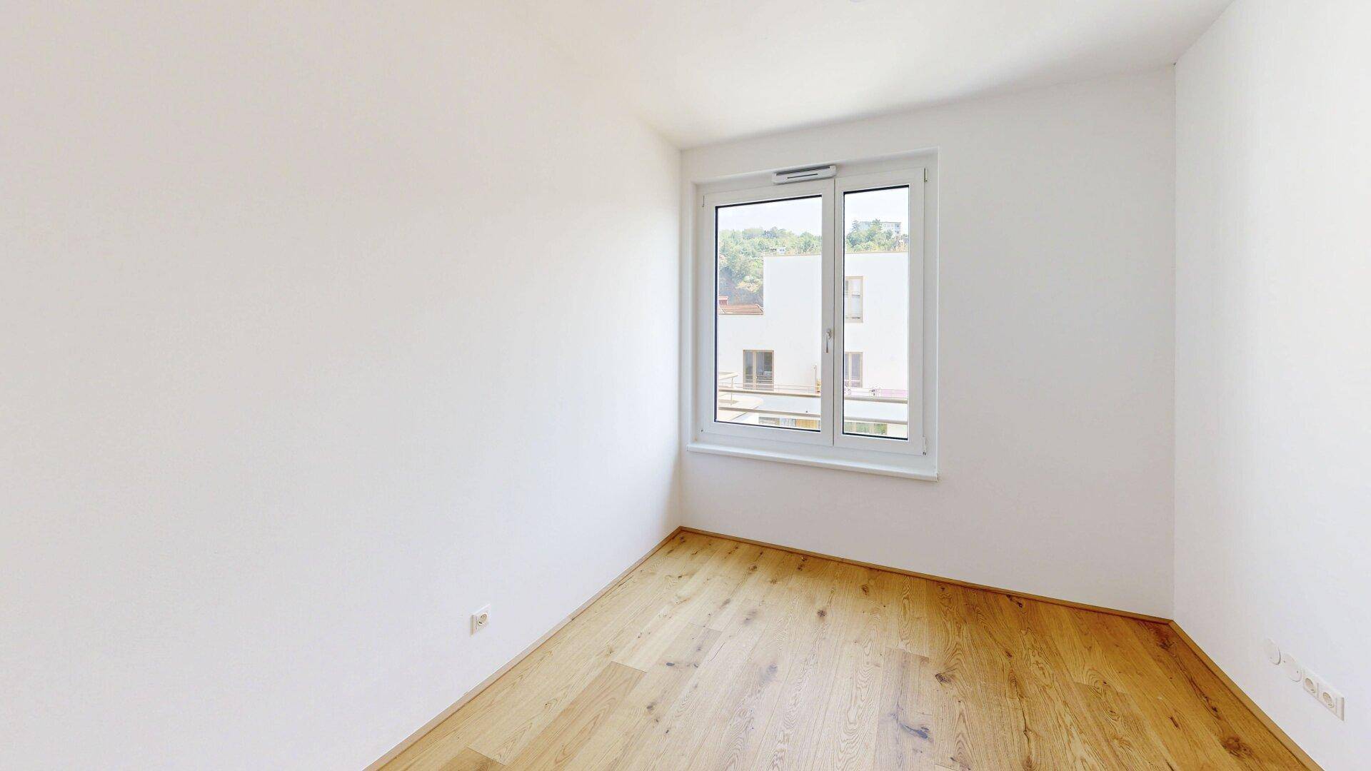 Ruhiges Schlafzimmer mit Holzboden und einem Fenster, das viel Tageslicht hereinlässt.