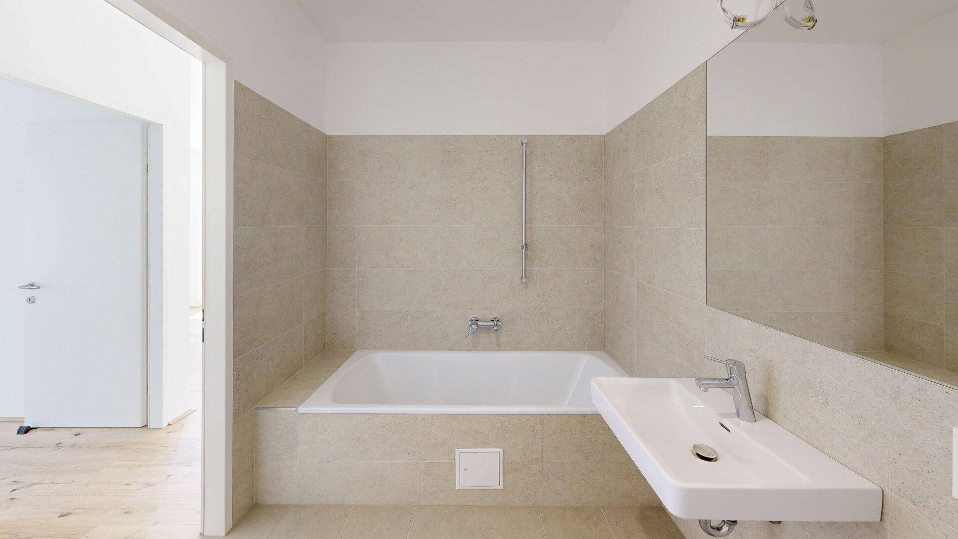 Modernes Badezimmer mit Badewanne, Einzelwaschbecken und beigefarbenen Fliesen.
