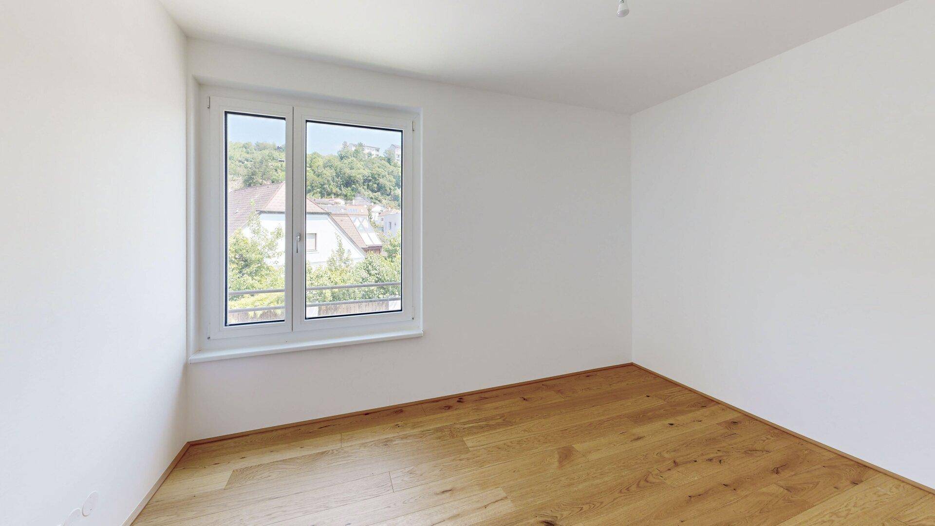 Ruhiges Zimmer mit Eichenparkettboden und Fenster mit Blick ins Grüne.
