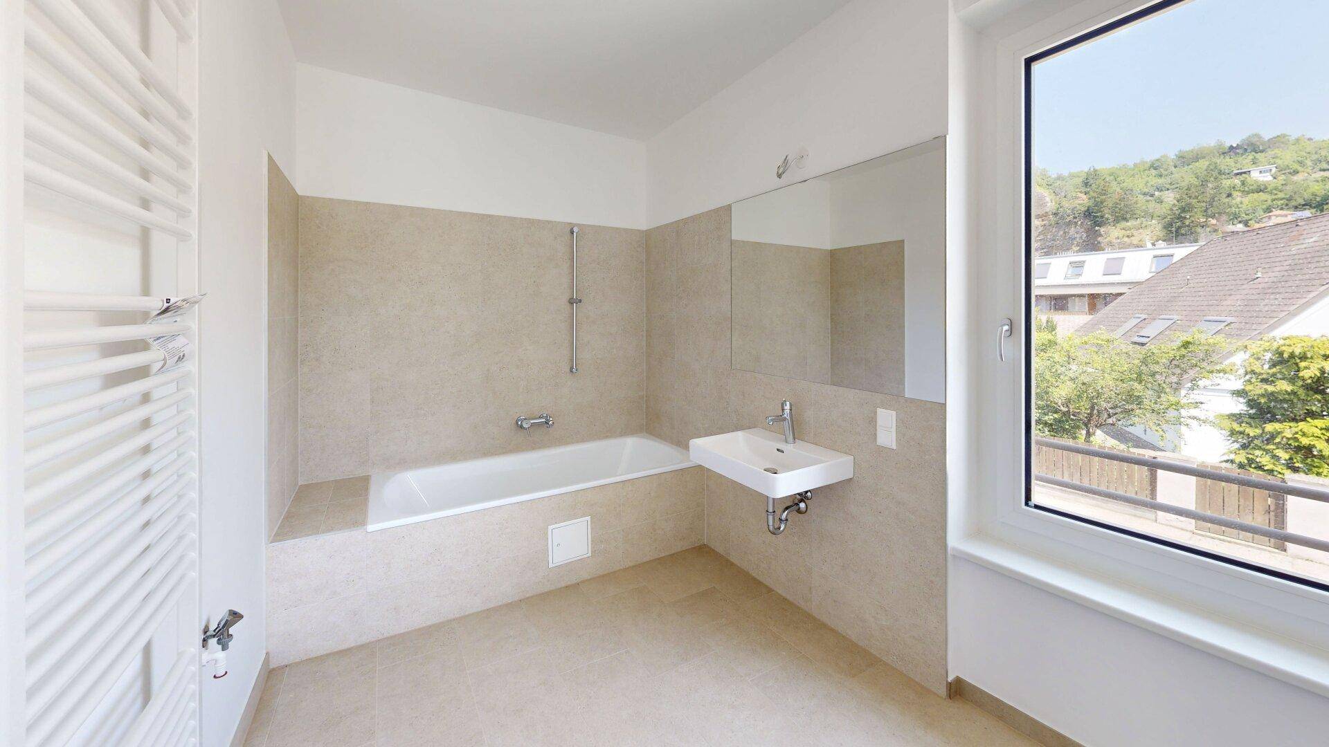 Modernes Badezimmer mit Badewanne, Waschbecken und großem Fenster für Tageslicht.