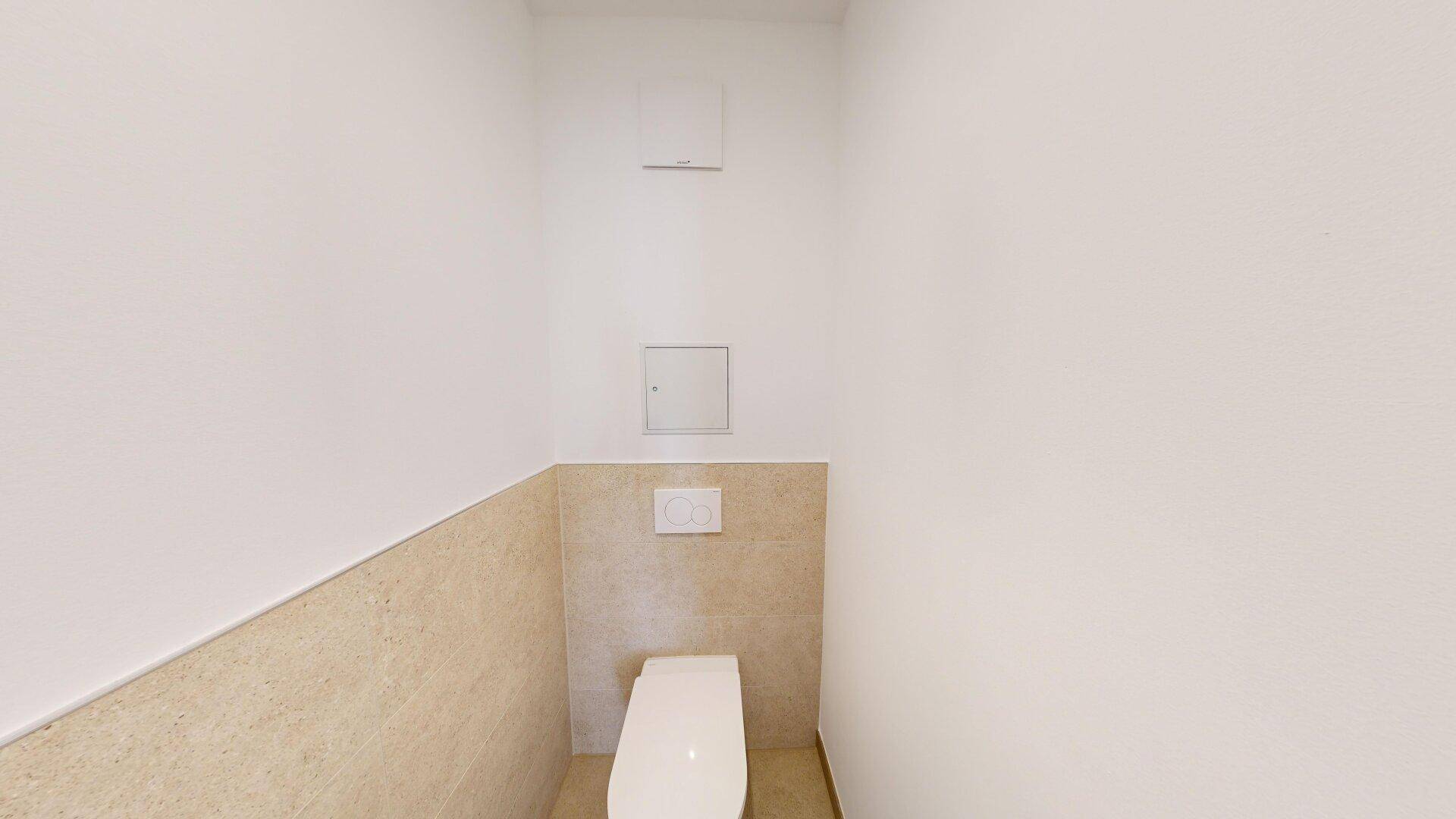 Separates Gäste-WC mit wandmontierter Toilette und hellen Fliesen an der Wand.