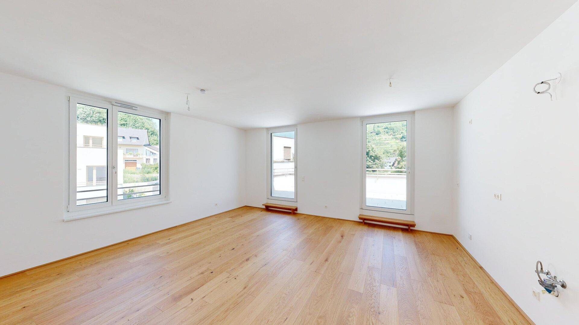Helles, leeres Zimmer mit großen Fenstern und neuem Holzparkettboden, bereit zur Einrichtung.