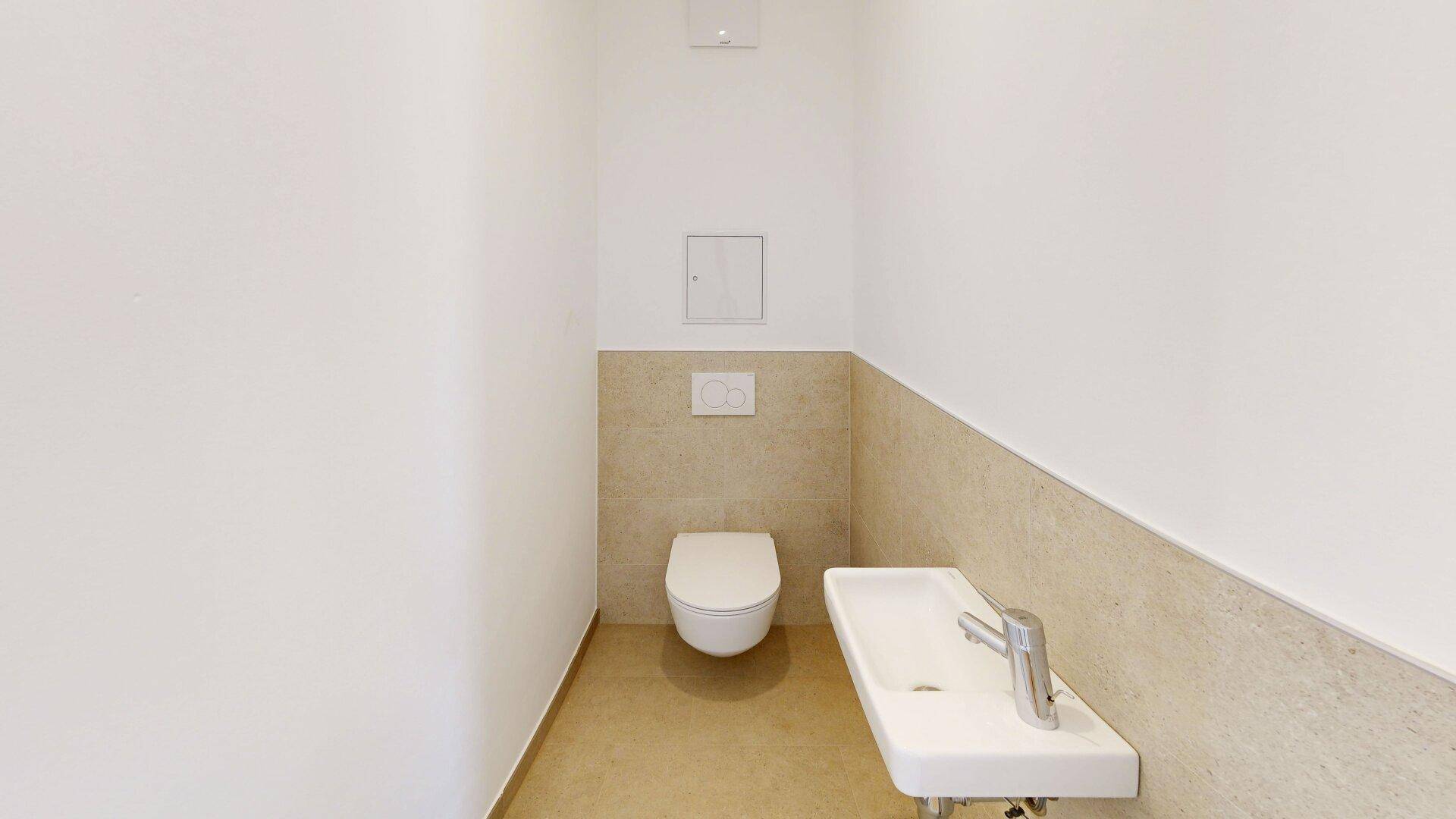 Funktionelles Gäste-WC mit wandhängender Toilette und kleinem Waschbecken, hell gefliest.