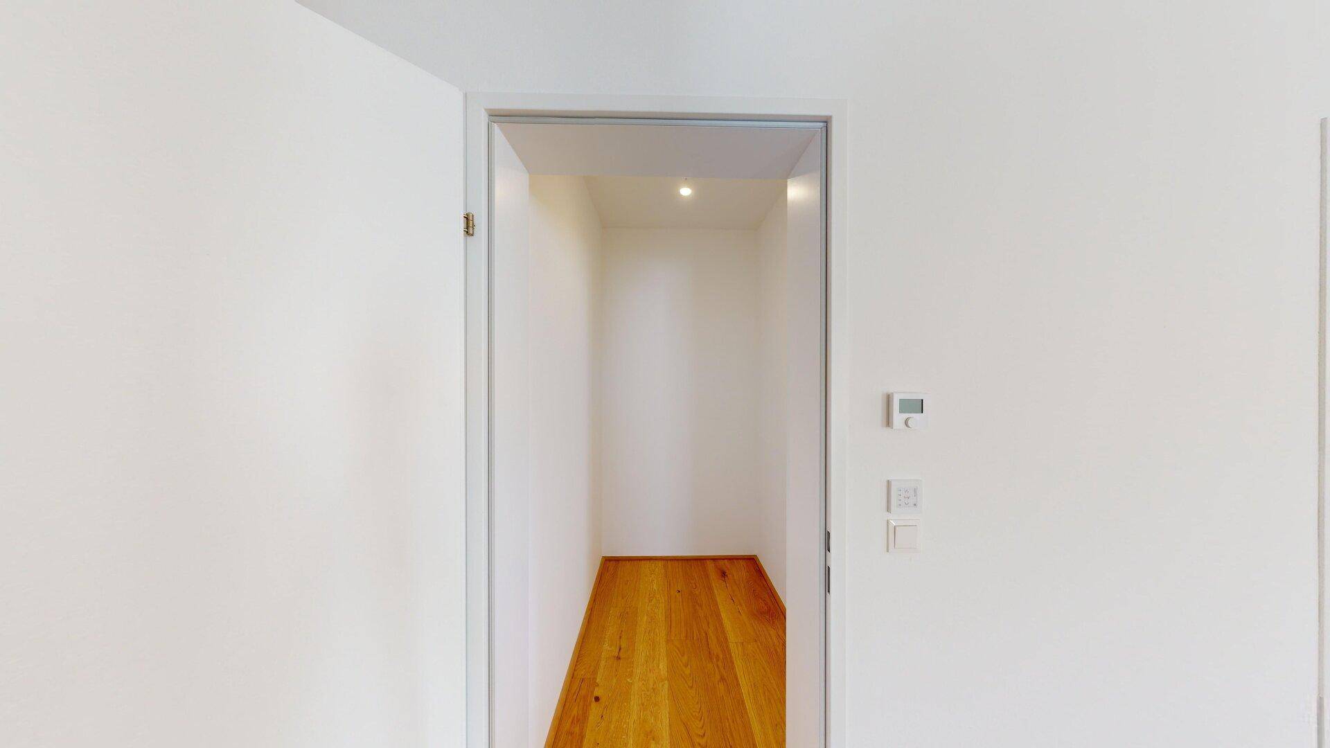 Praktischer Abstellraum mit Holzboden und Deckenbeleuchtung, ideal für zusätzlichen Stauraum.