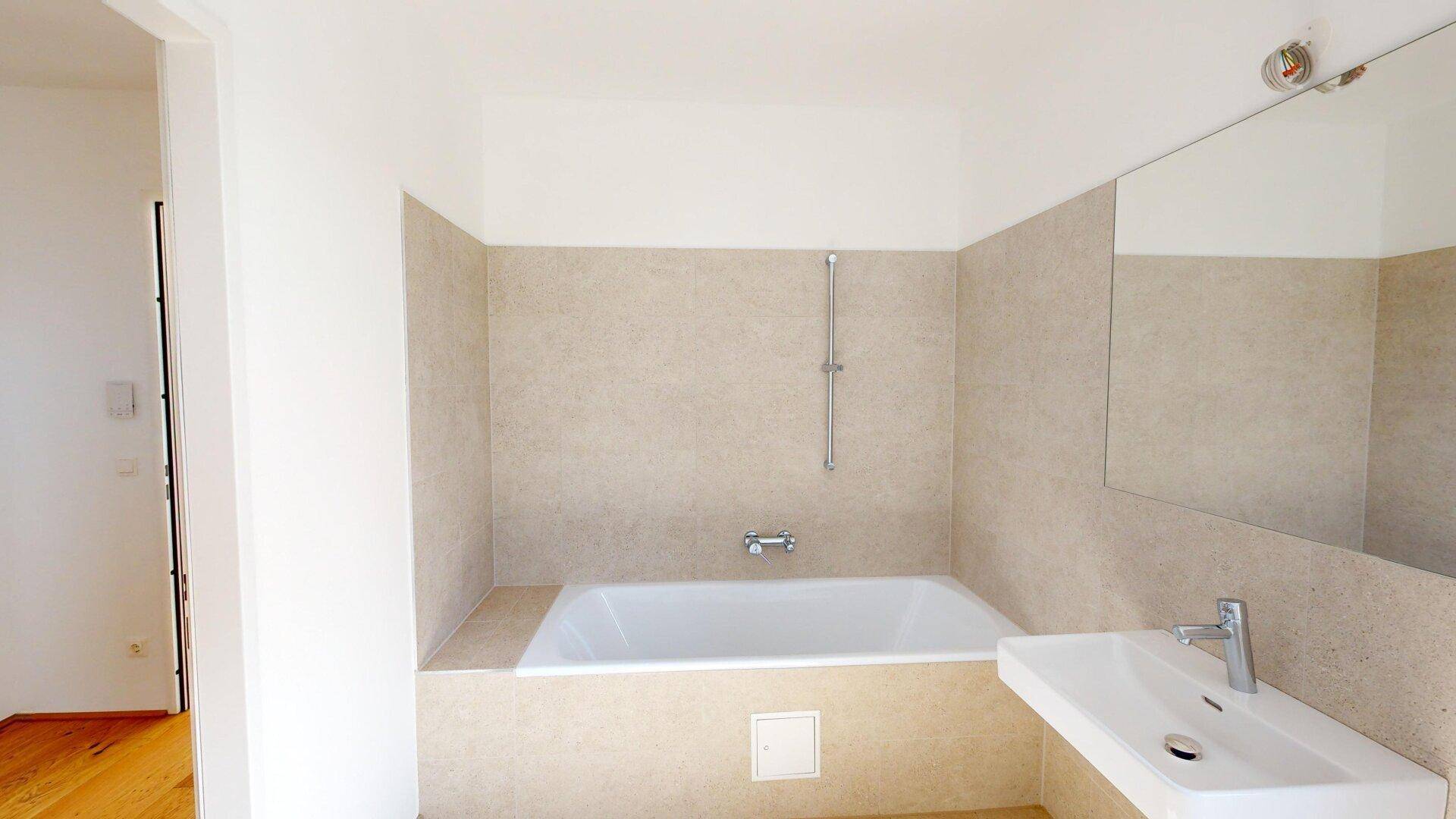 Modernes Badezimmer mit integrierter Badewanne, Einzelwaschbecken und beigefarbenen Fliesen.