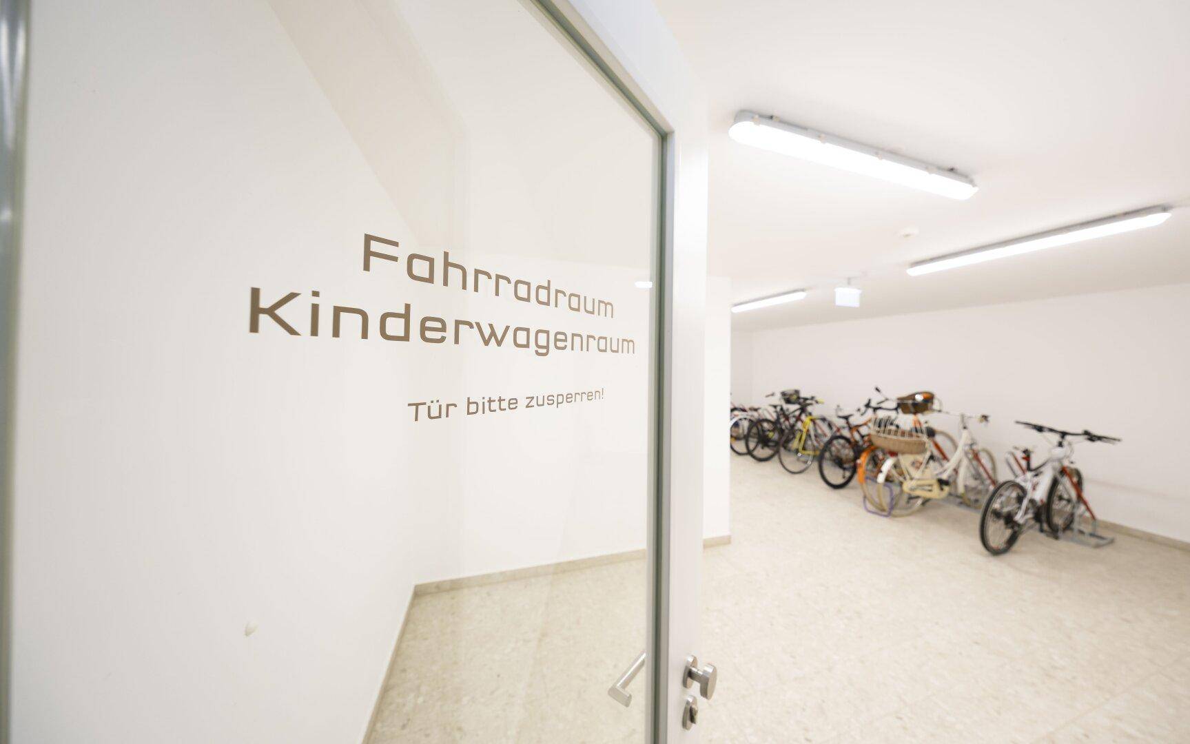 Geräumiger Fahrrad- und Kinderwagenraum mit mehreren Fahrrädern und hellem Fliesenboden.