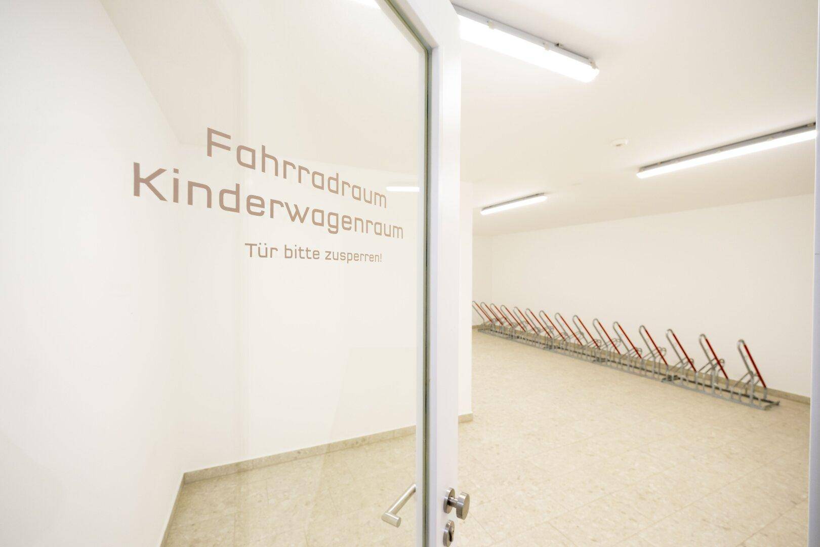 Geräumiger Fahrrad- und Kinderwagenraum mit Fliesenboden und Abstellmöglichkeiten.