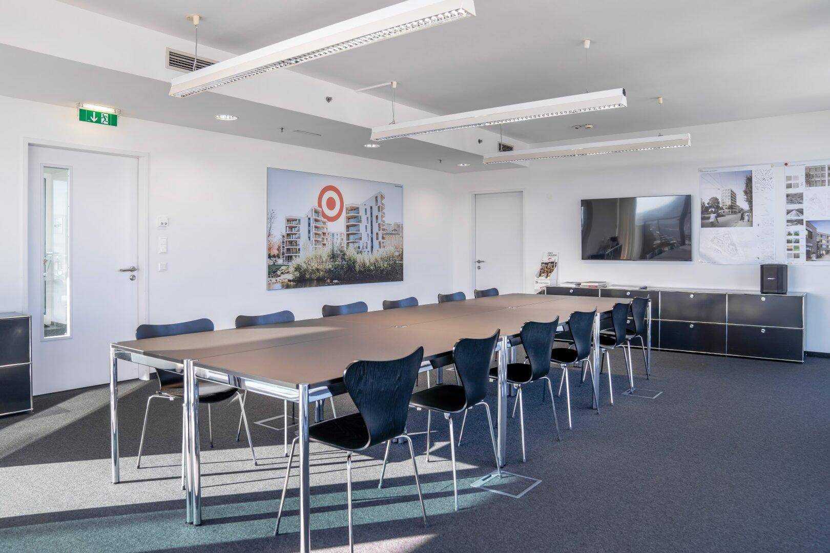 Moderner Konferenzraum mit großem Bildschirm, Sideboard und Kunstwerk an der Wand, ideal für Präsentationen.