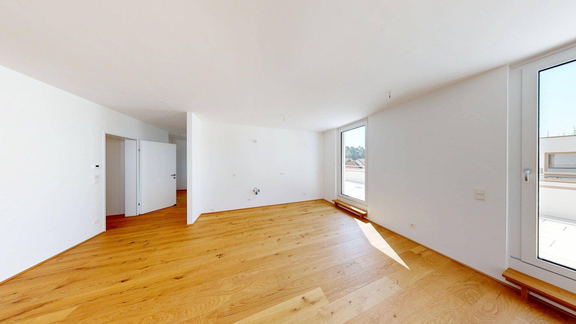 Heller, unmöblierter Raum mit Parkettboden und Zugang zu einem Außenbereich durch große Fenstertüren.