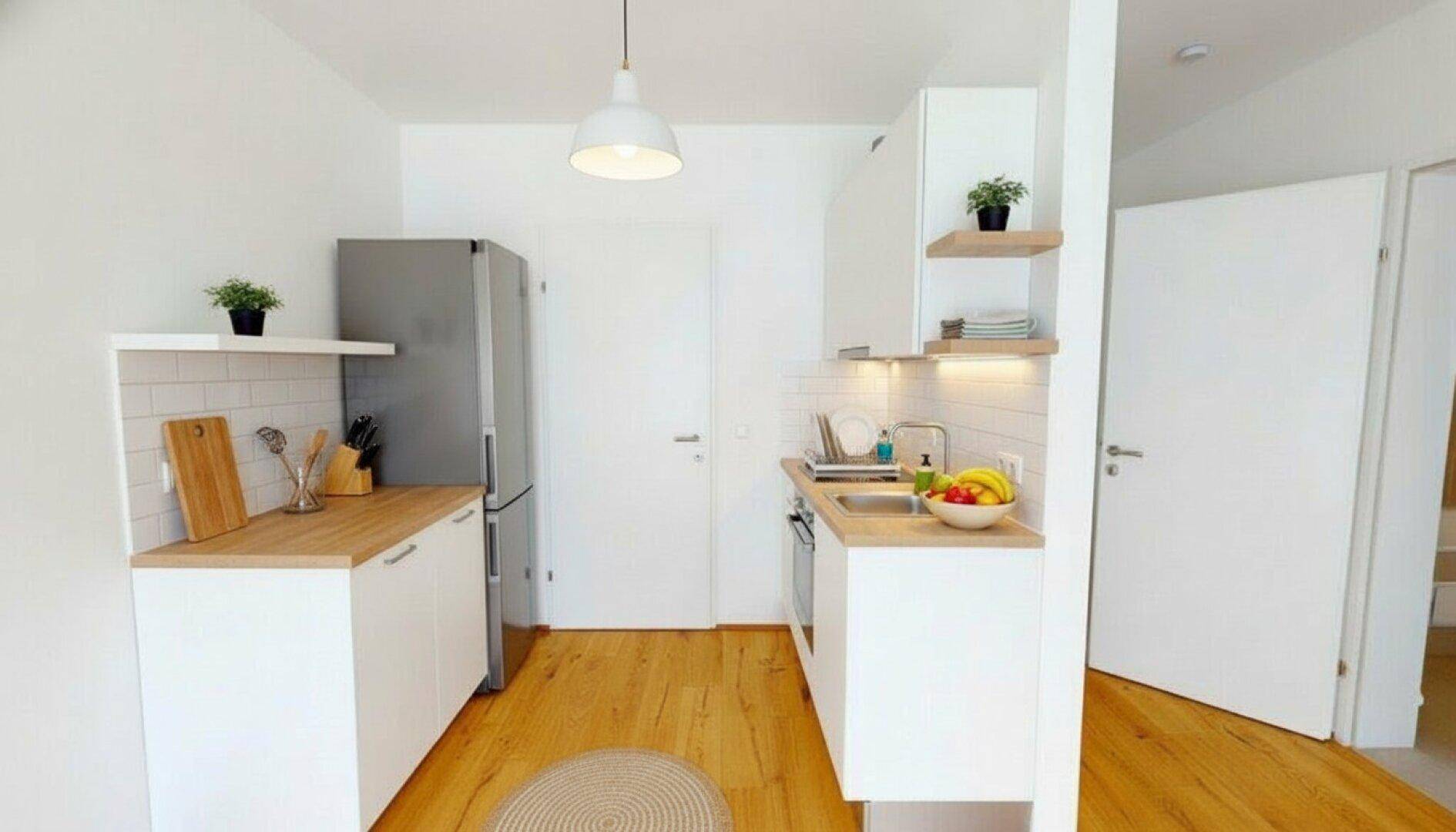 Moderne, kompakte Küche mit weißen Schränken, Holztheke und integrierten Geräten.