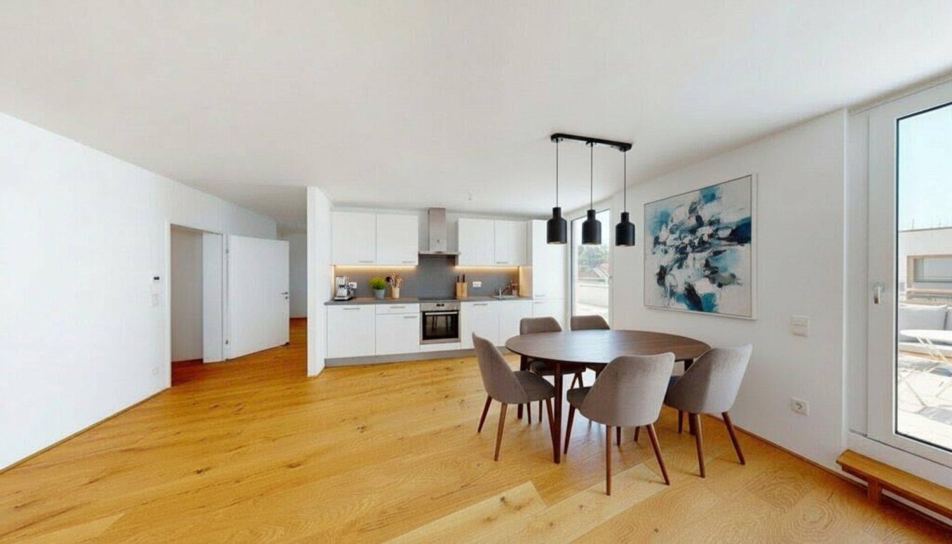 Offener Wohn-Essbereich mit moderner weißer Einbauküche und hellem Parkettboden.