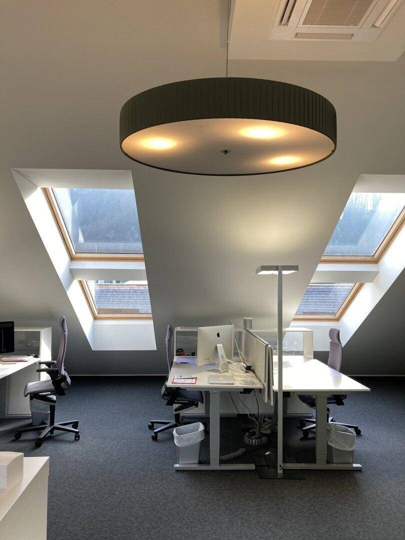 Heller Bürobereich im Dachgeschoss mit mehreren Arbeitsplätzen und großen Dachfenstern.