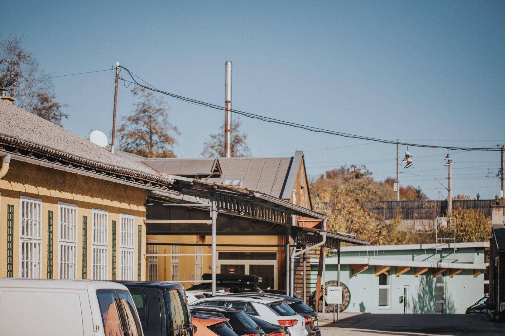 Außenansicht mehrerer Gebäude mit unterschiedlichen Fassaden und geparkten Autos.