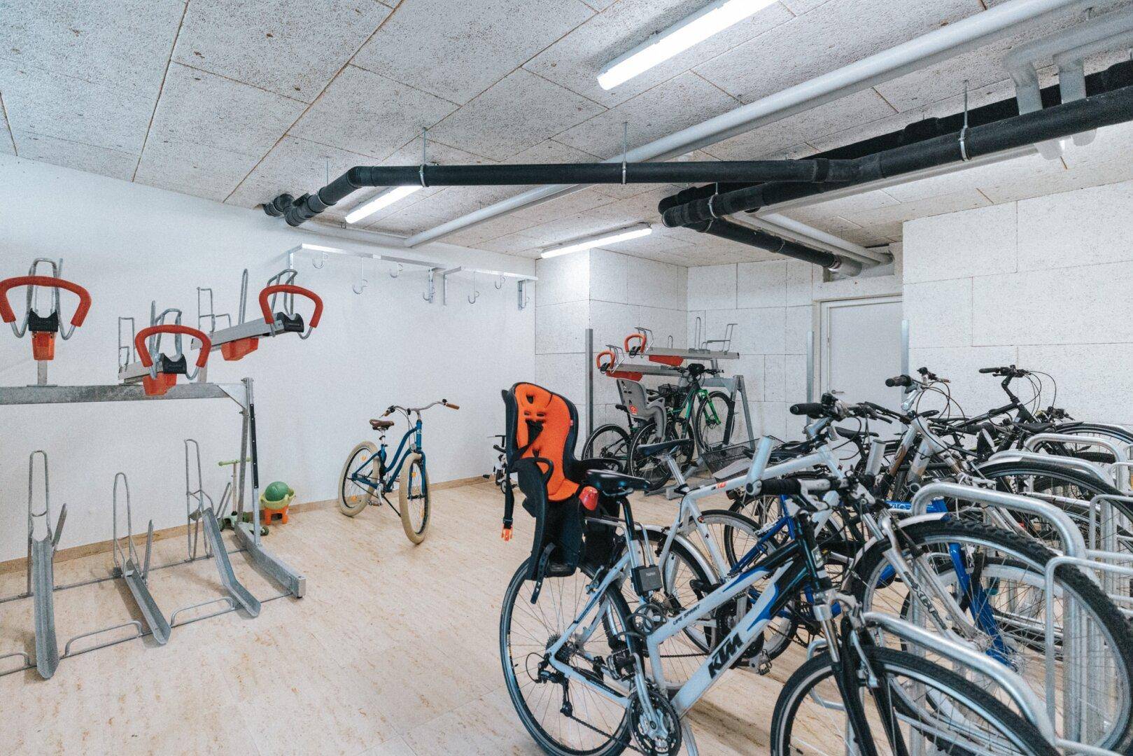 Geräumiger Fahrradraum mit vielen Stellplätzen und moderner Beleuchtung.