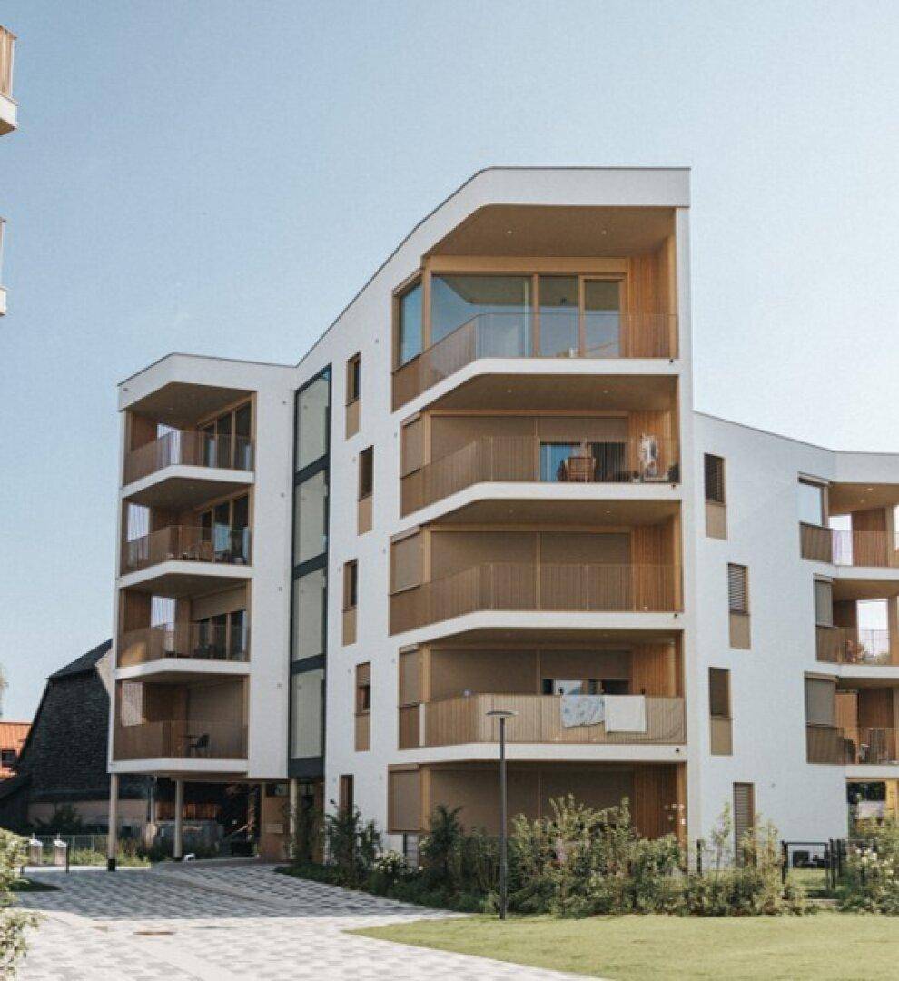 Elegantes Mehrfamilienhaus mit geschwungenen Balkonen und moderner Architektur.