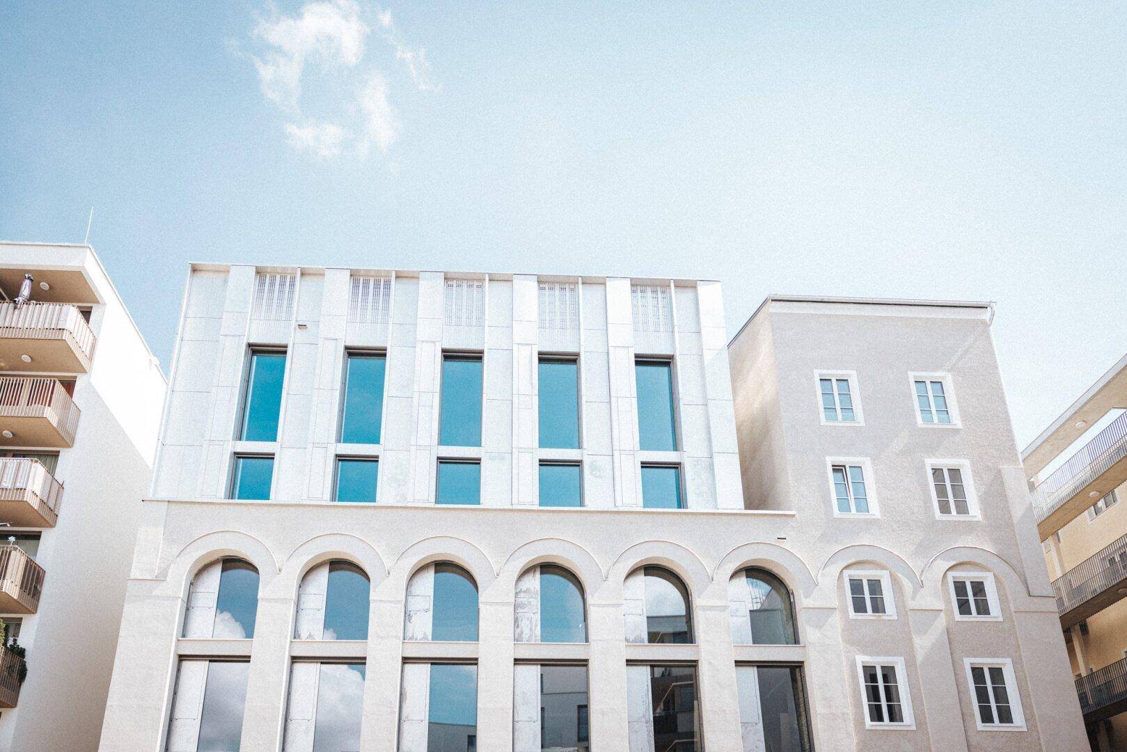 Helle Gebäudefassade mit einer Kombination aus modernen und klassischen Architekturelementen.