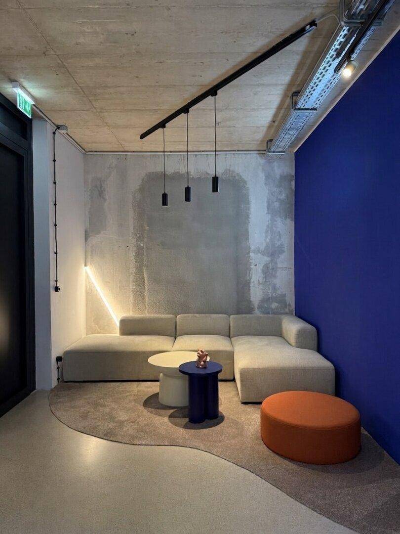 Gemütlicher Loungebereich mit Ecksofa, Couchtisch und einer Akzentwand in leuchtendem Blau.