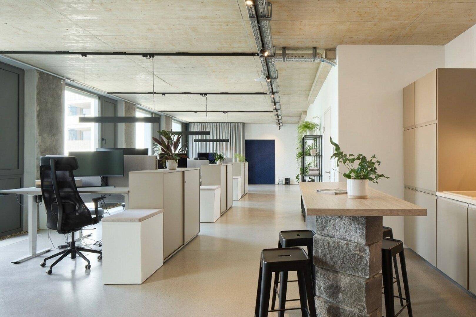 Großraumbüro mit modernen Arbeitsplätzen, Sichtbetondecke und industriellem Design.