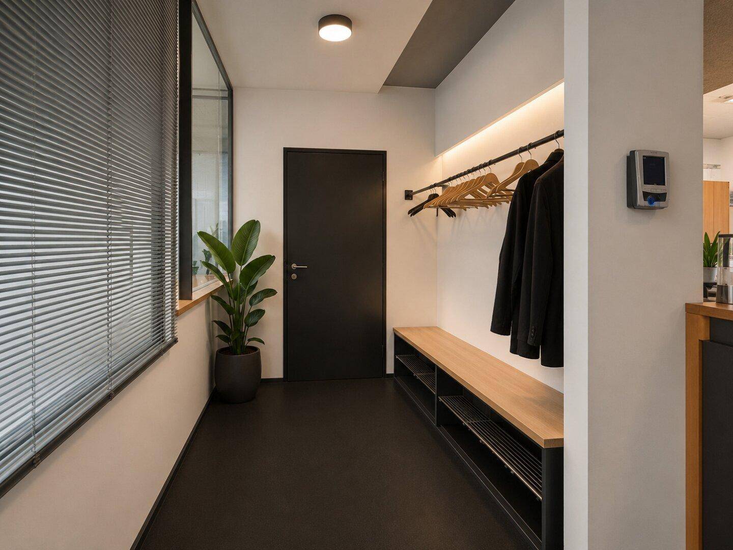 Moderner Flur mit Garderobe, Sitzbank und dunklem Bodenbelag, neben einem Fenster mit Jalousien.