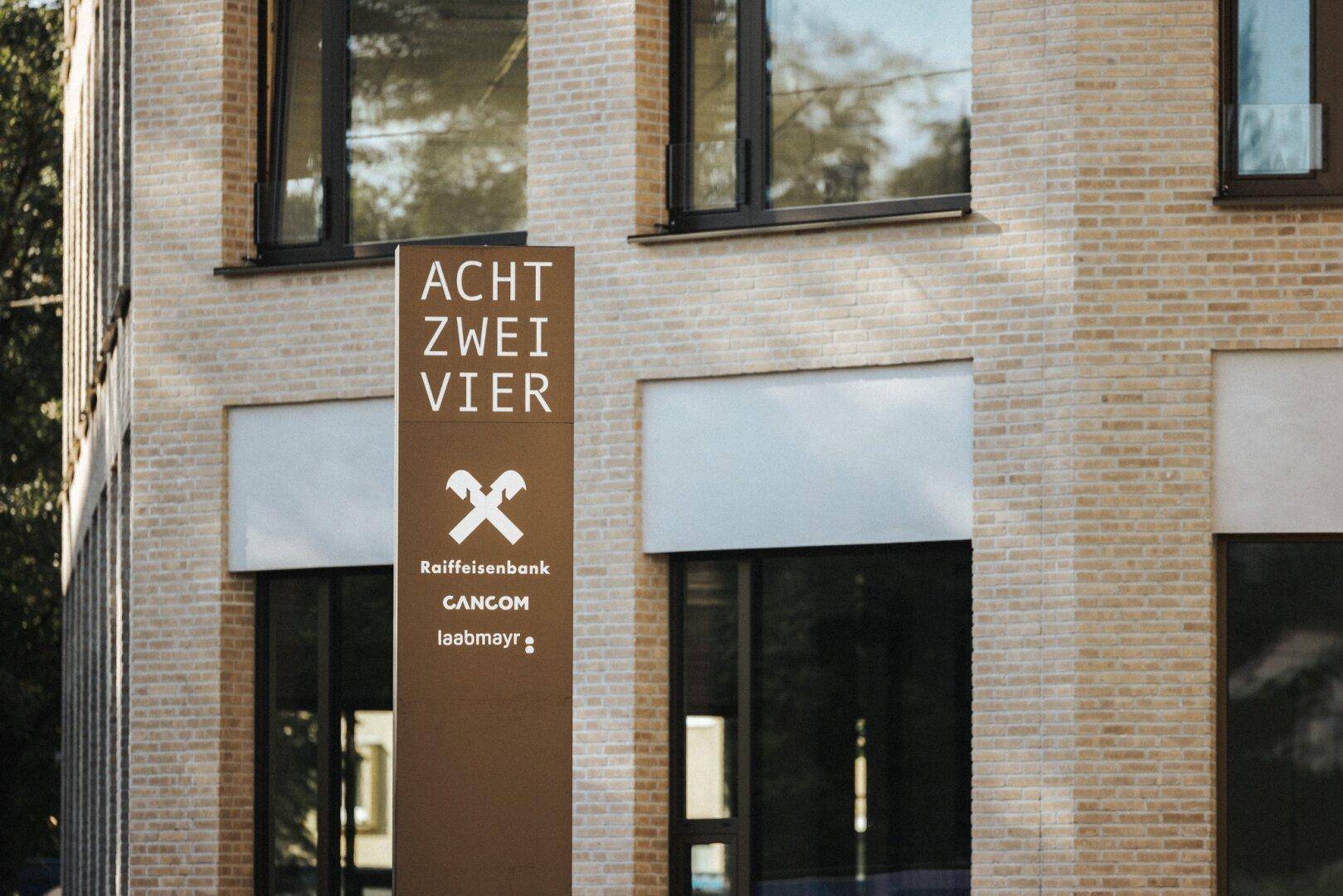 Moderne Ziegelfassade eines Geschäftsgebäudes mit großen Fenstern und einem prominenten Firmenschild.