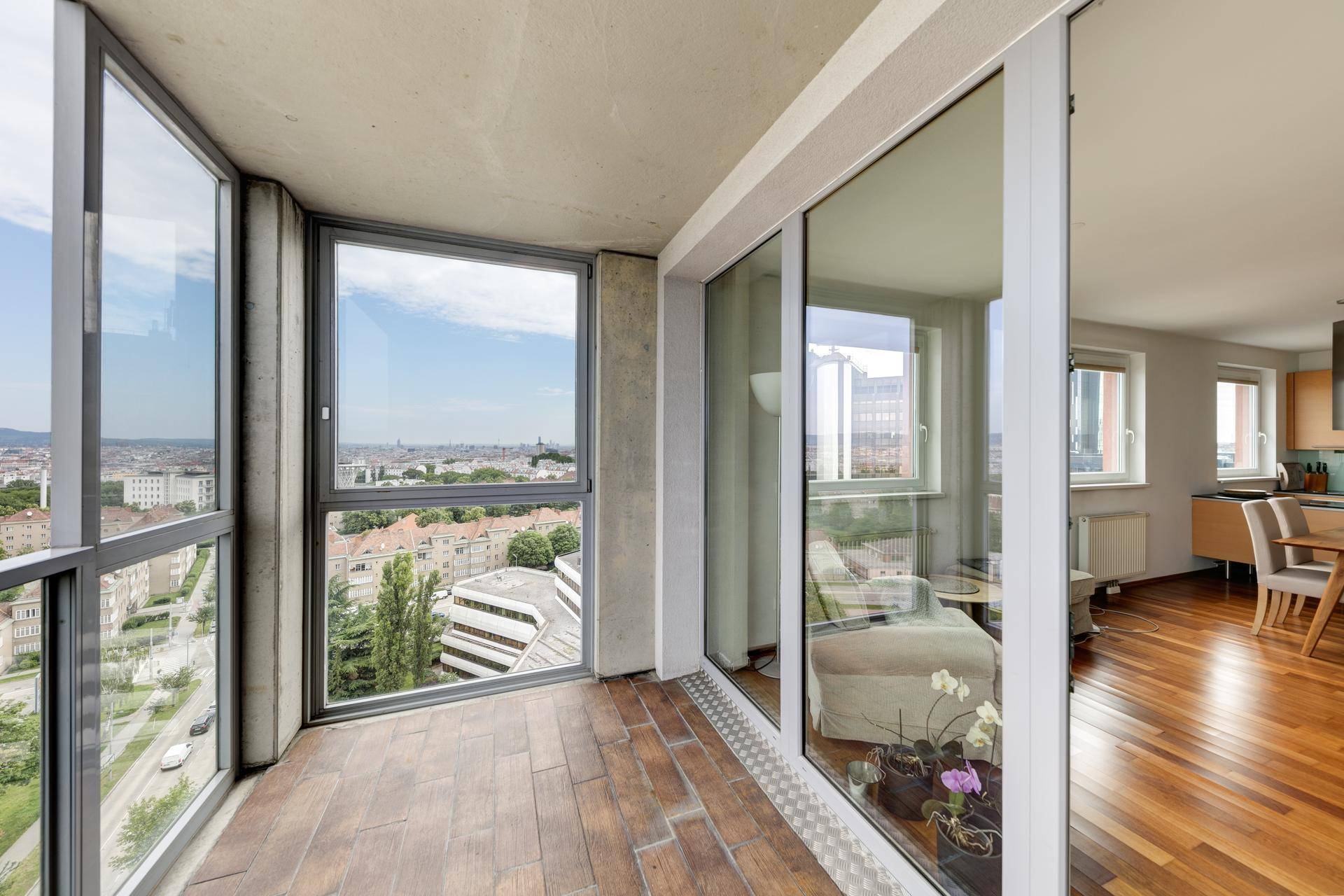 Verglaster Balkon mit Fliesenboden und weitem Blick über die Stadt.