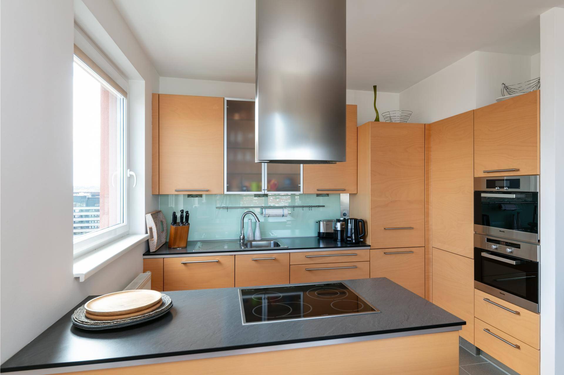 Moderne Holzküche mit Kochinsel, Induktionskochfeld und Dunstabzugshaube.