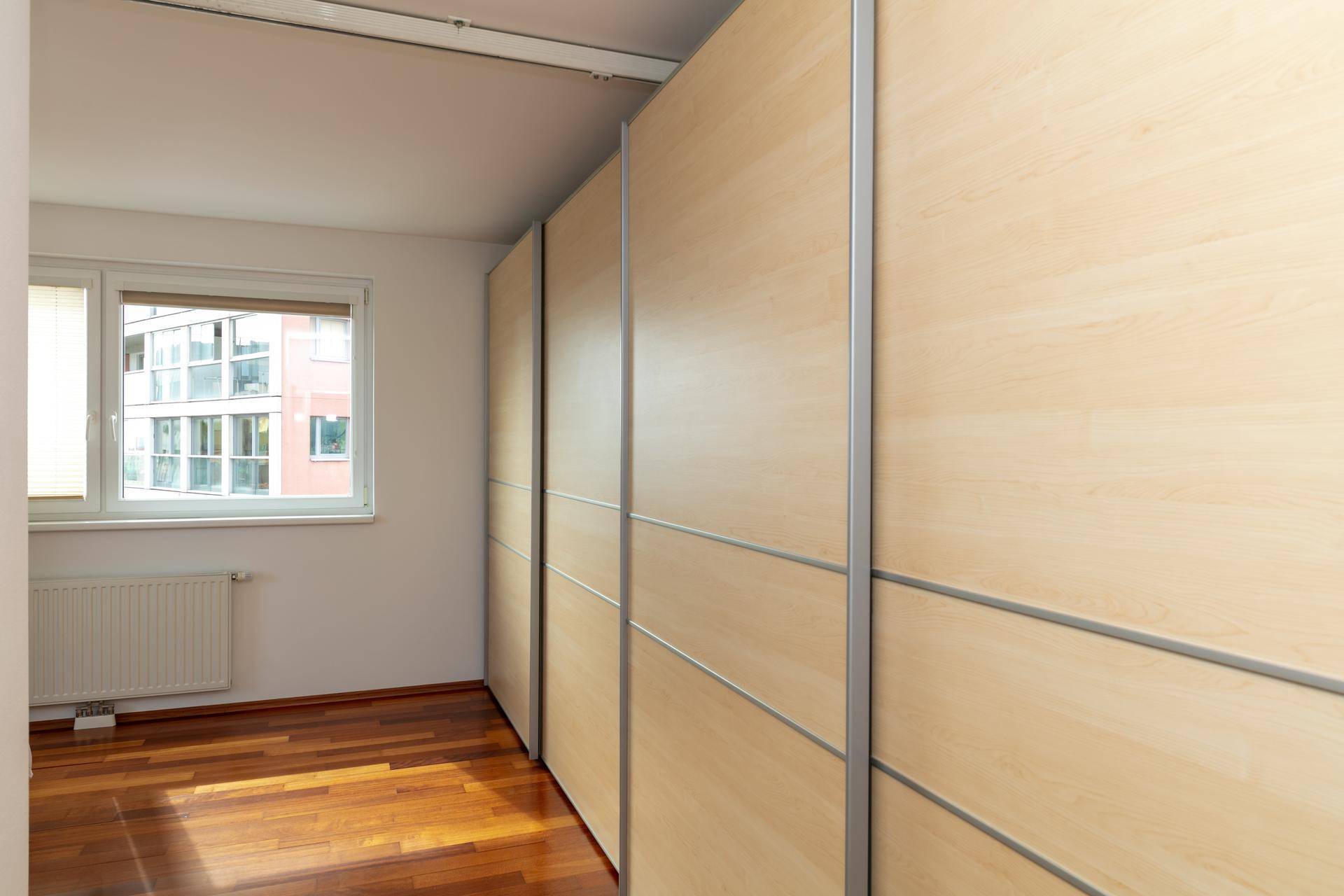Schlafzimmer mit Holzparkettboden und großen Einbauschränken entlang einer Wand.