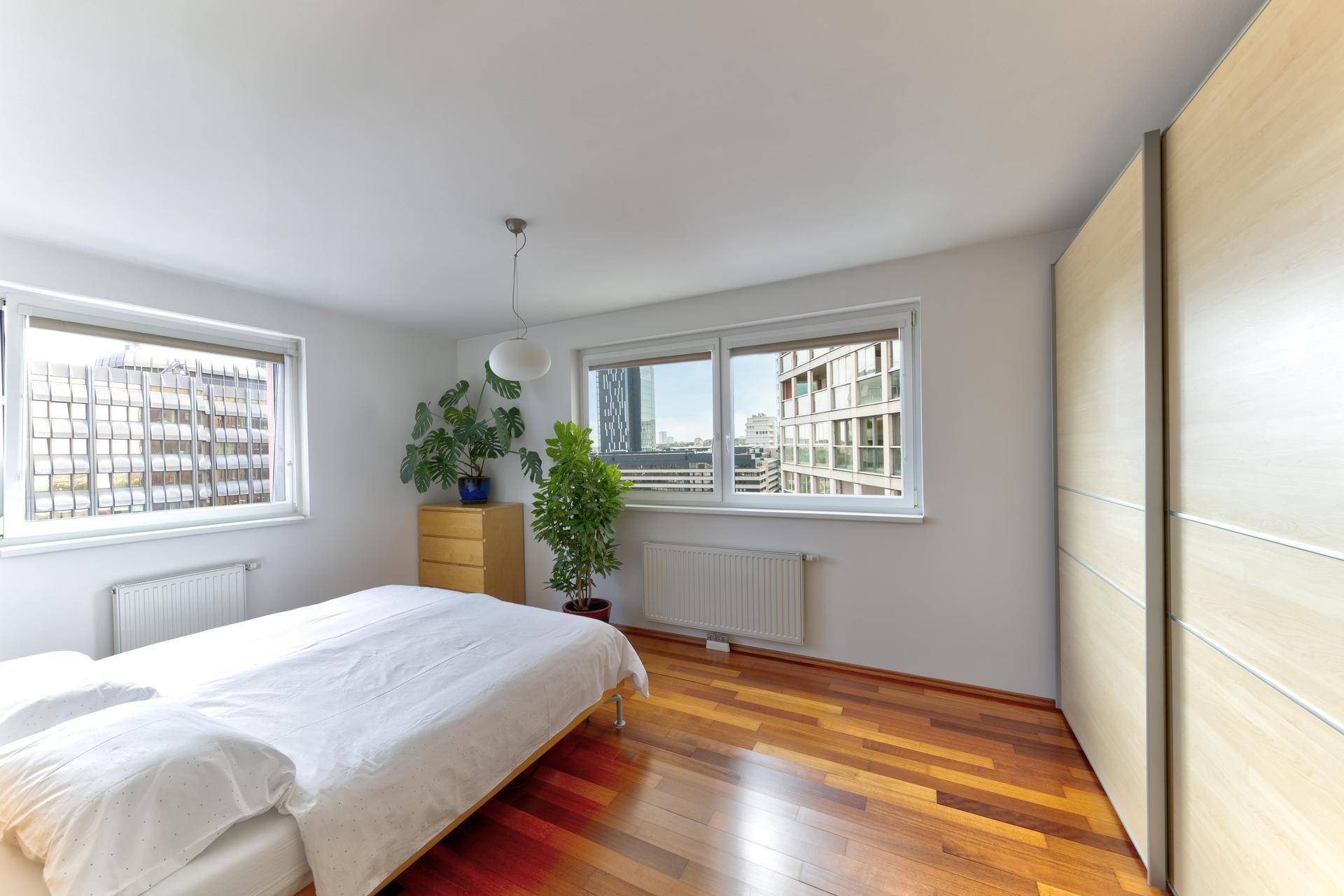 Schlafzimmer mit Holzparkettboden, Doppelbett und Einbauschrank mit Schiebetüren.