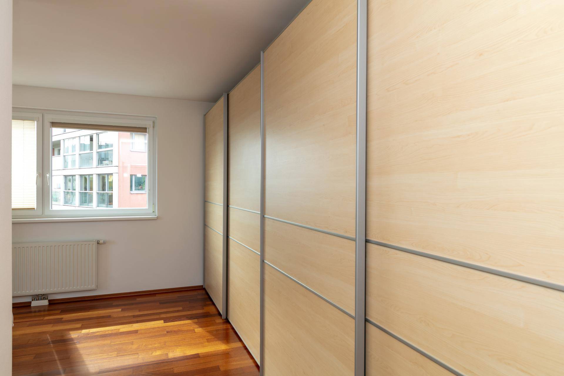 Schlafzimmer mit Holzparkettboden und großen Einbauschränken entlang einer Wand.