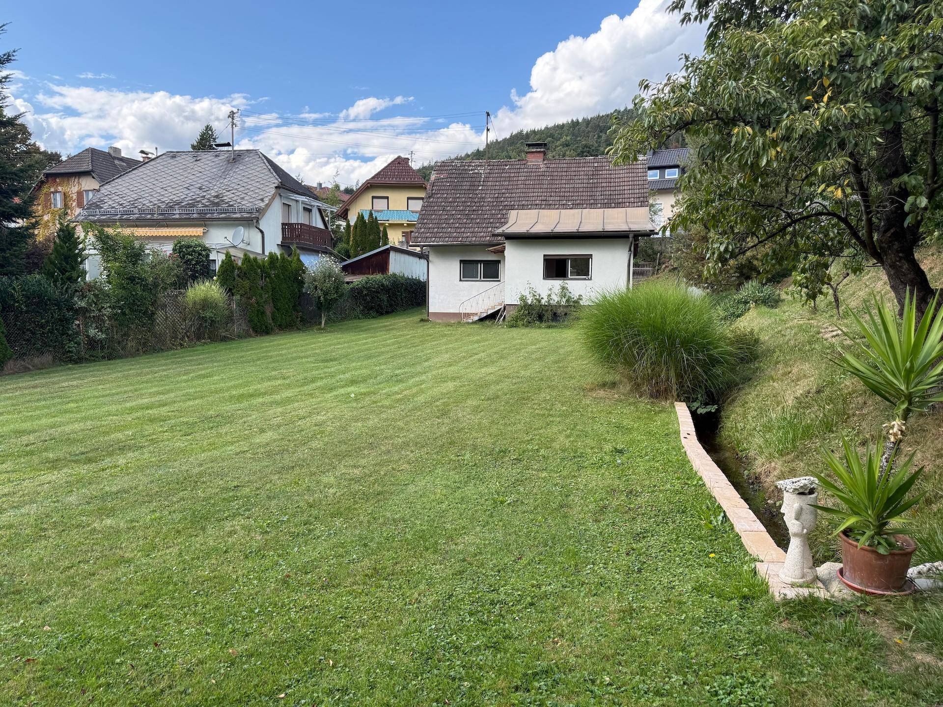 Gepflegte Rasenfläche mit Blick auf das Haus und umliegende Bebauung.