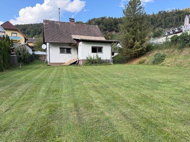 Hausansicht von der großen Rasenfläche aus mit Blick auf die Umgebung.