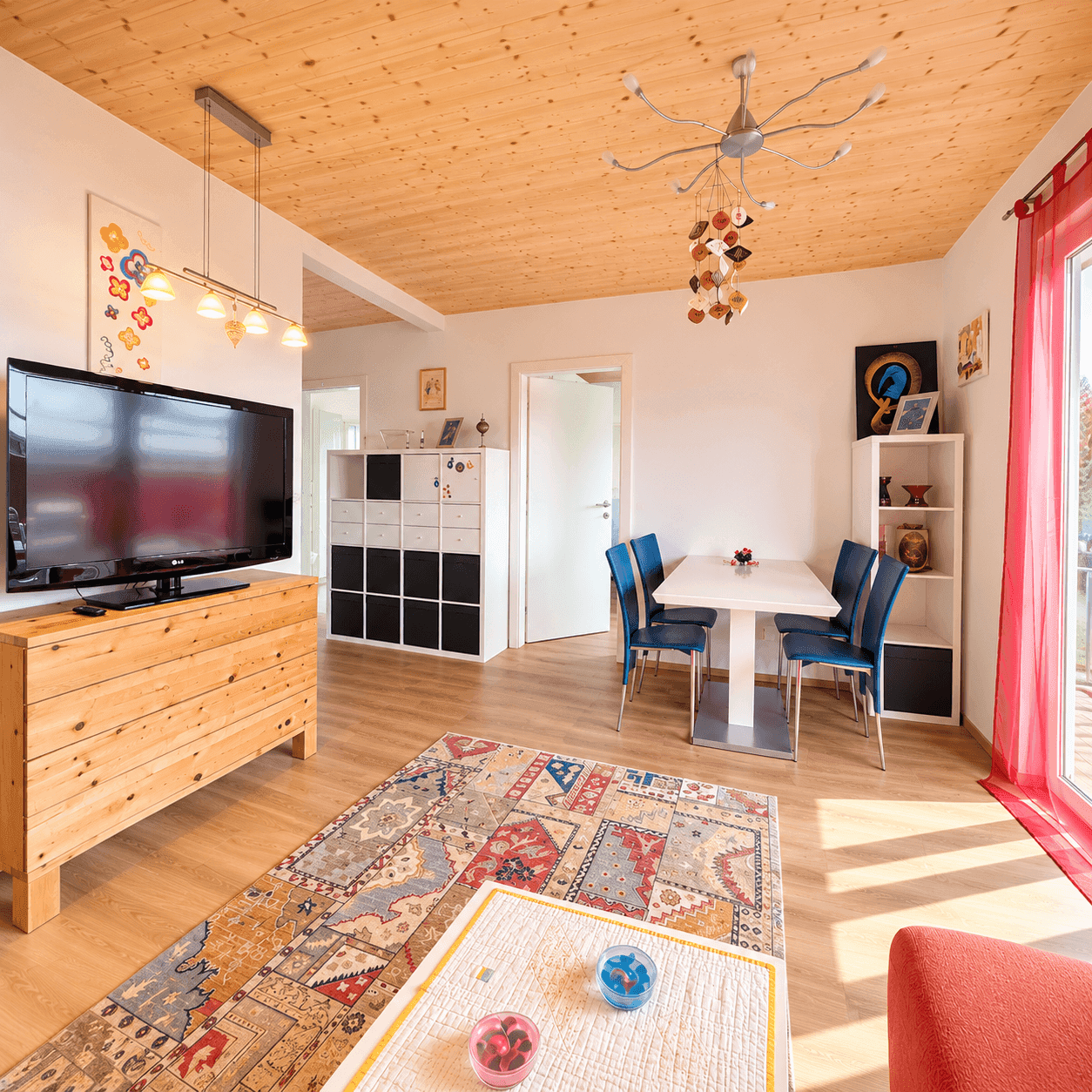 Heller Wohn- und Essbereich mit Holzbalkendecke, Parkettboden und Zugang zum Balkon.