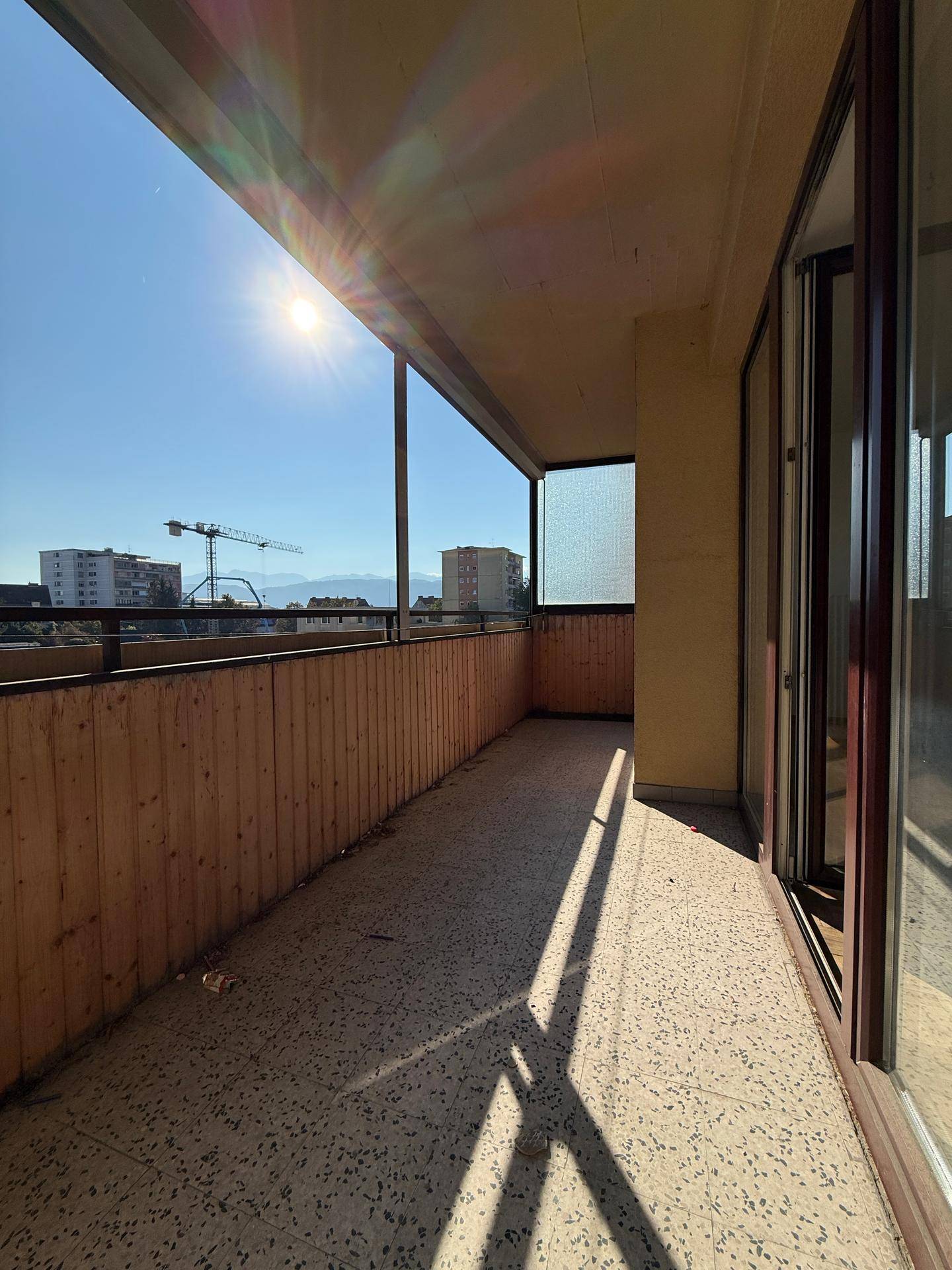 Langer Balkon mit Holzverkleidung und weitem Blick über die Stadt.