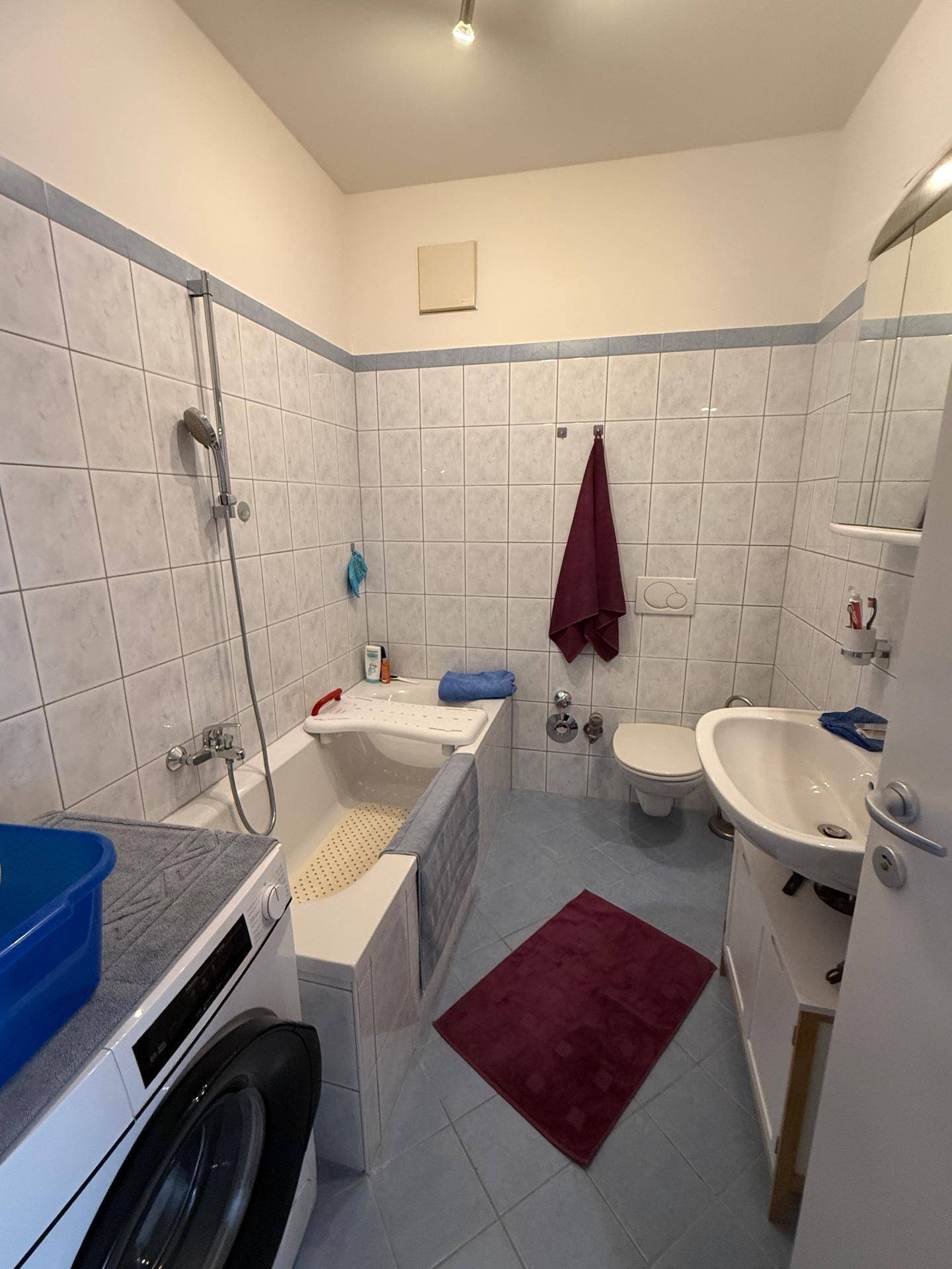 Funktionales Badezimmer mit Badewanne, WC und Waschbecken, ausgestattet mit hellblauen Fliesen.